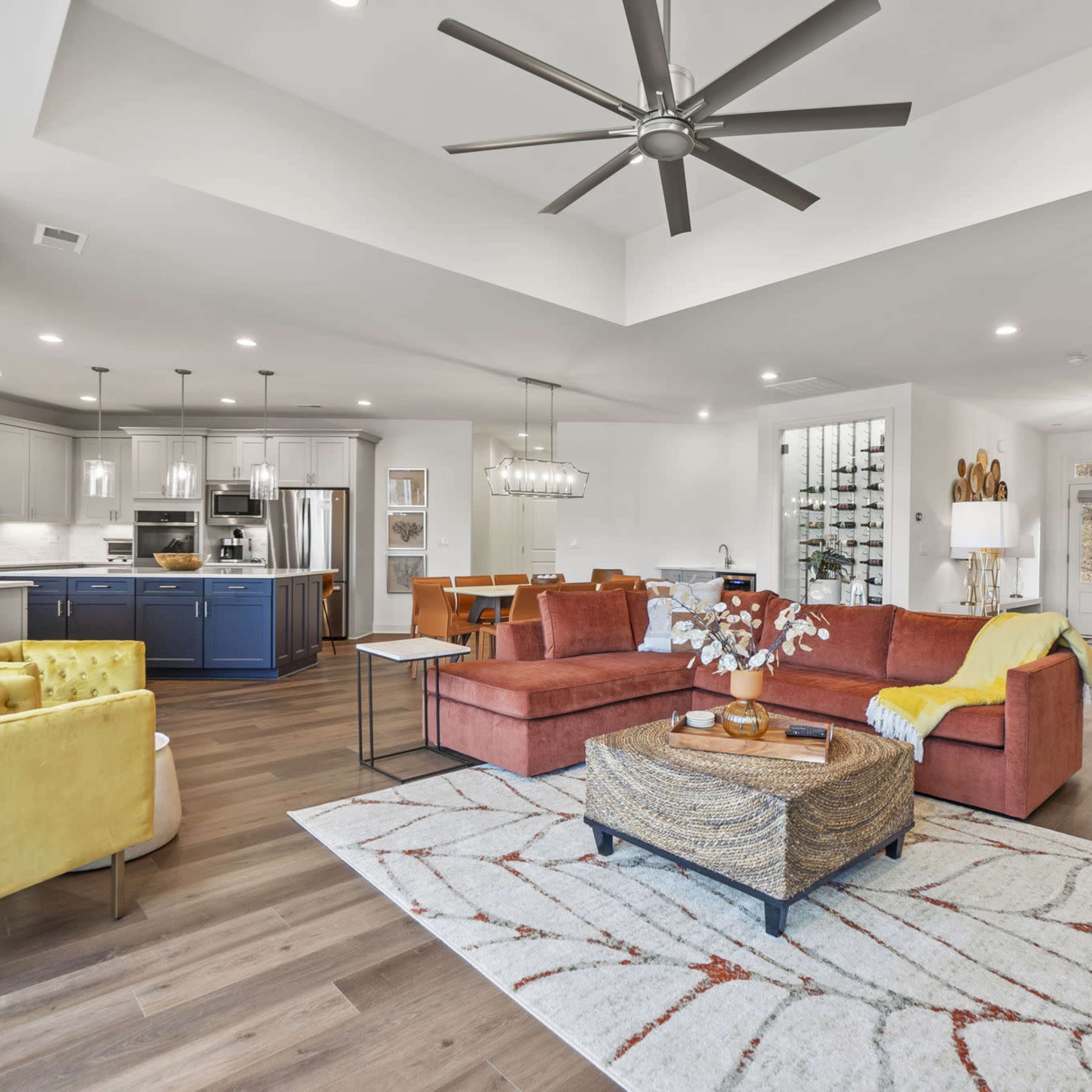 A modern living room with a large sectional sofa, a coffee table, and a bright open layout that connects to a kitchen area.