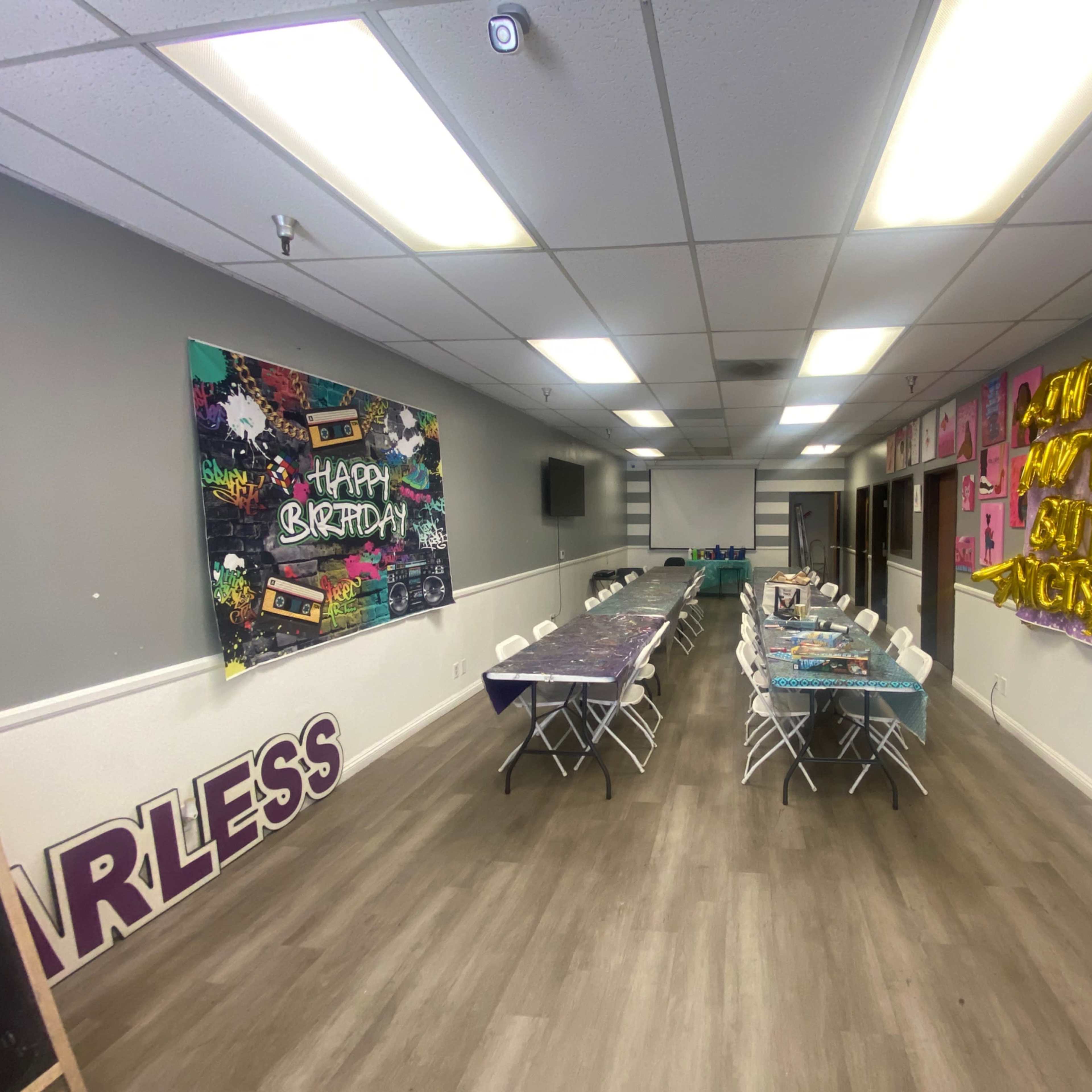 A spacious party room decorated with colorful banners and tables arranged for a birthday celebration.