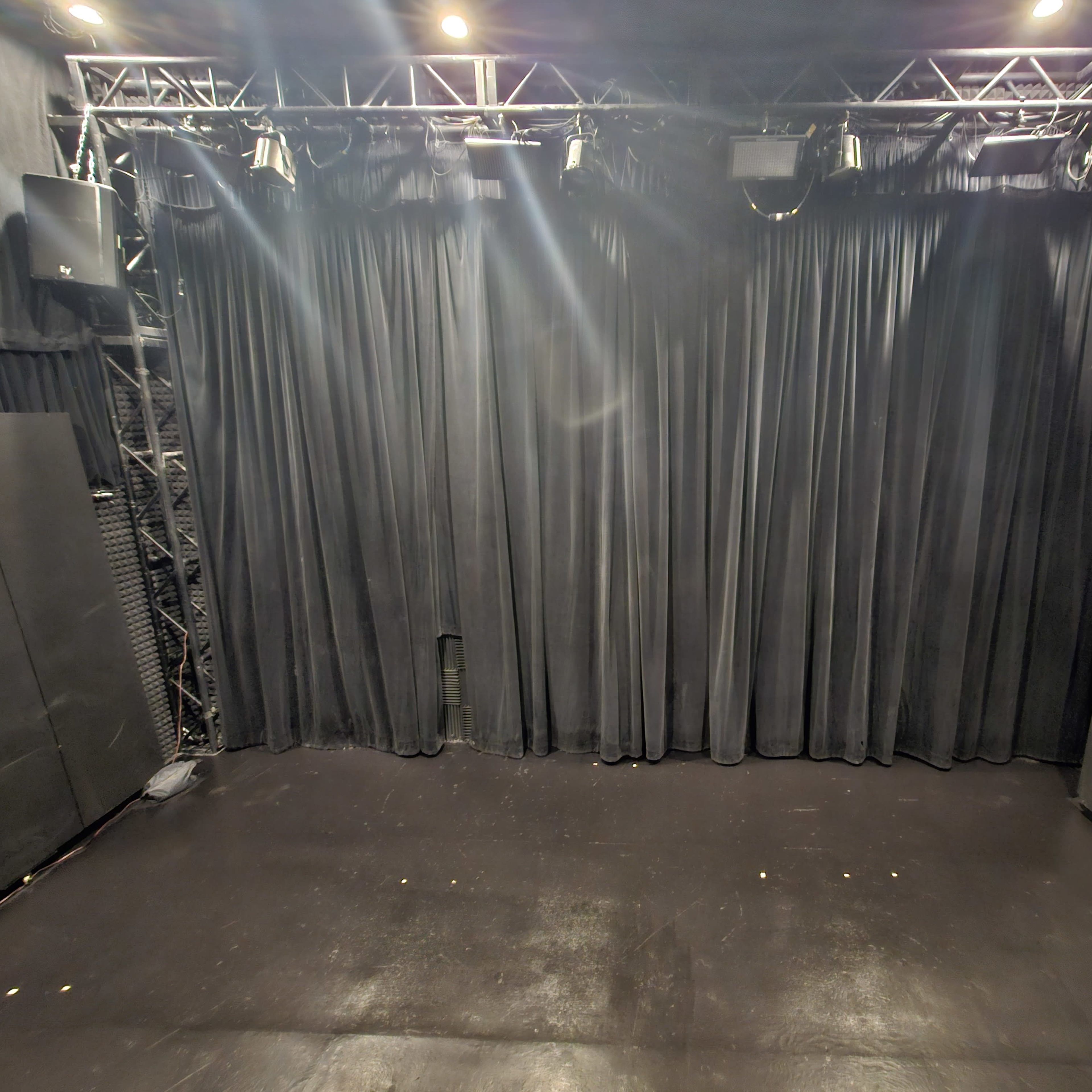 A stage area with black curtains in the background and sound equipment positioned on either side.