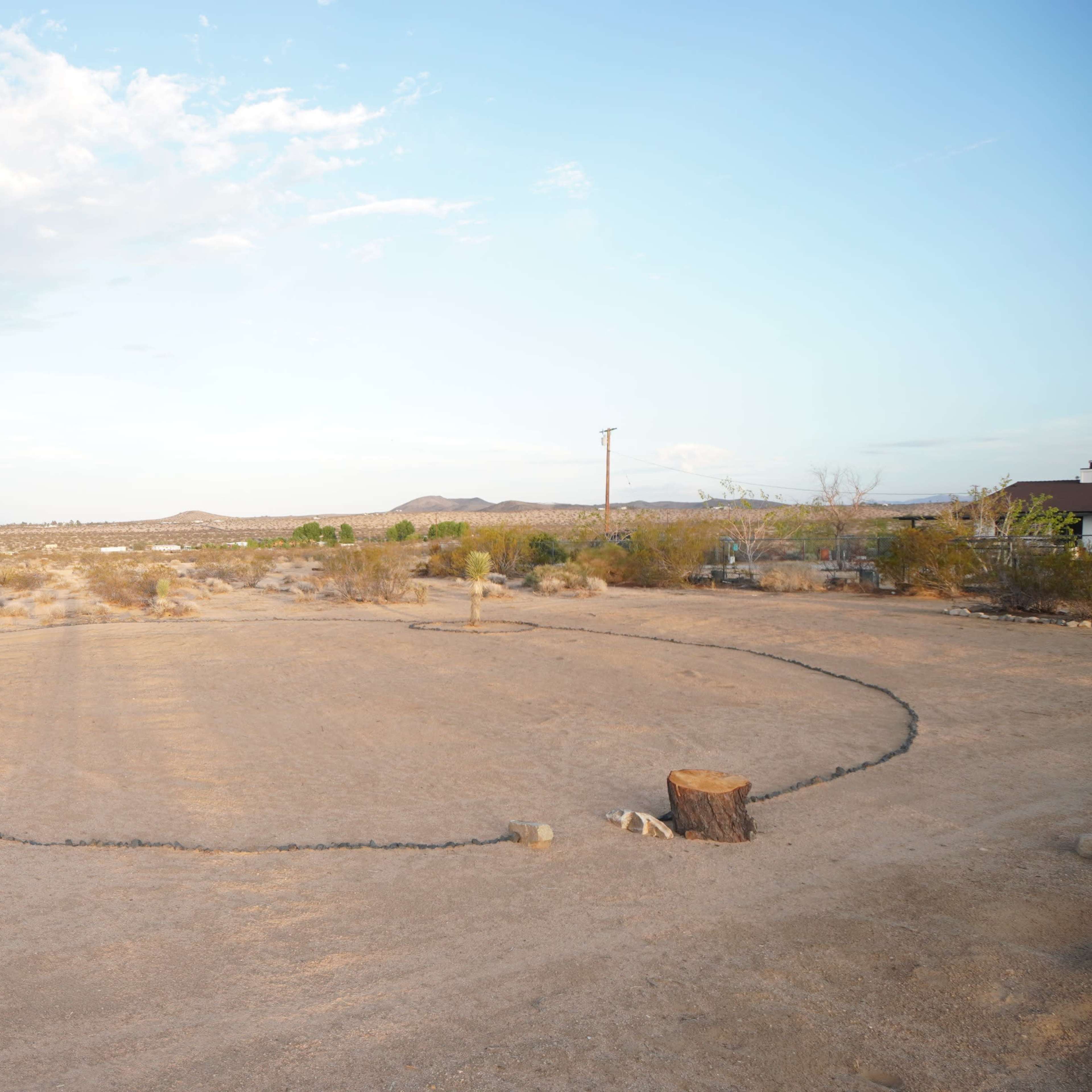 A circular area marked by a dark outline in a dry, desert landscape with sparse vegetation and distant hills.