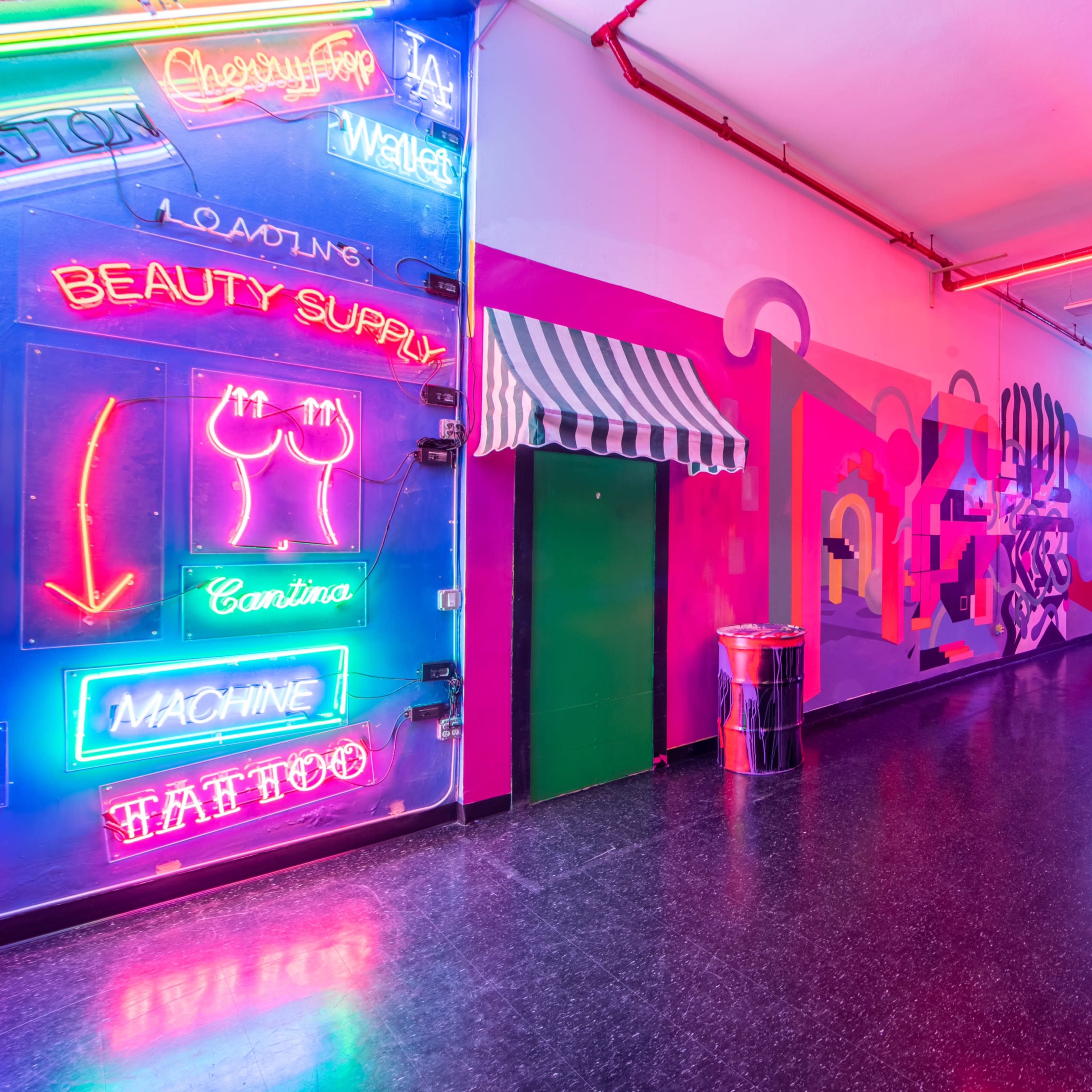 A brightly lit indoor space featuring colorful neon signs, including a beauty supply and tattoo shop, along with vibrant wall murals.