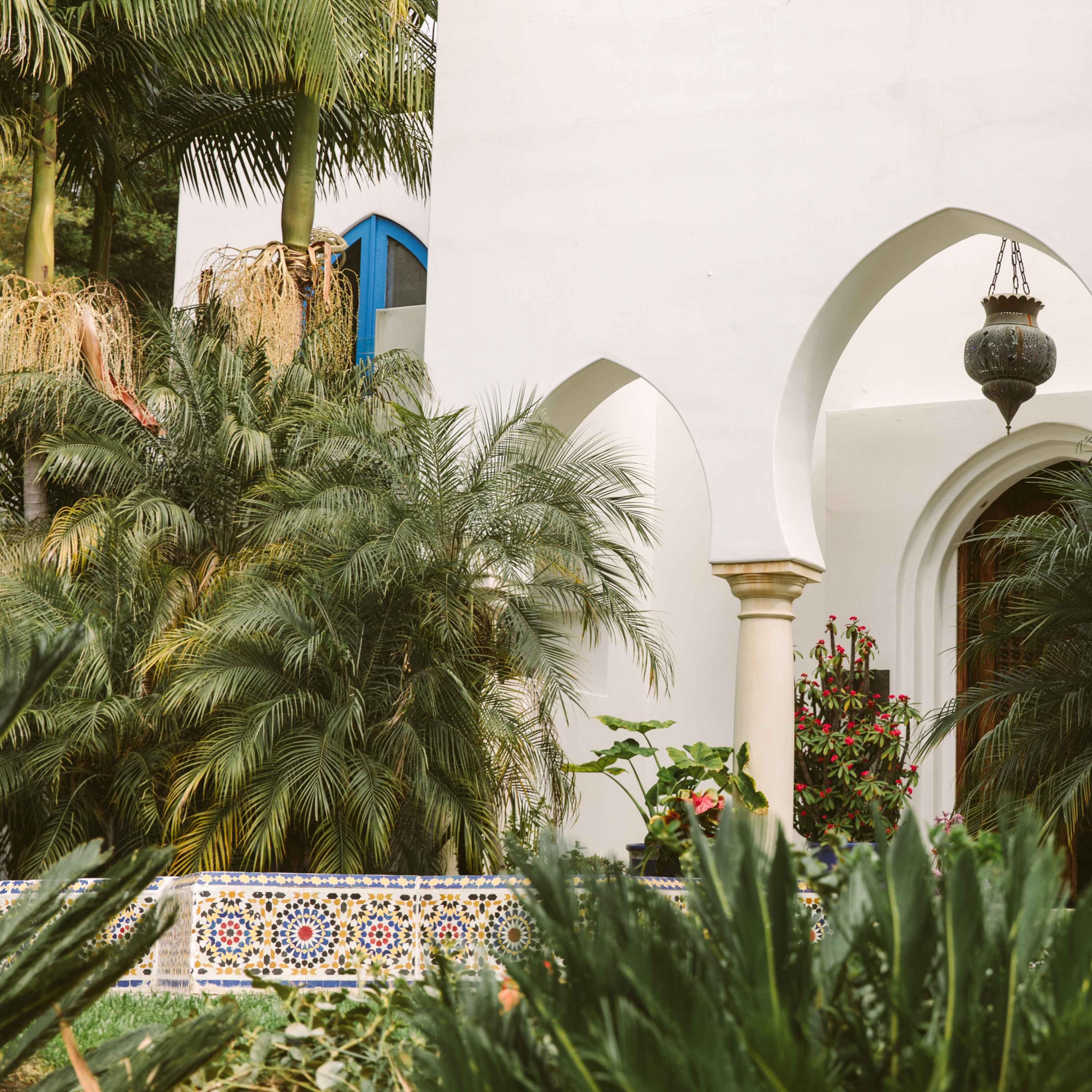 An arched doorway surrounded by lush greenery and decorative tiles in a garden setting.