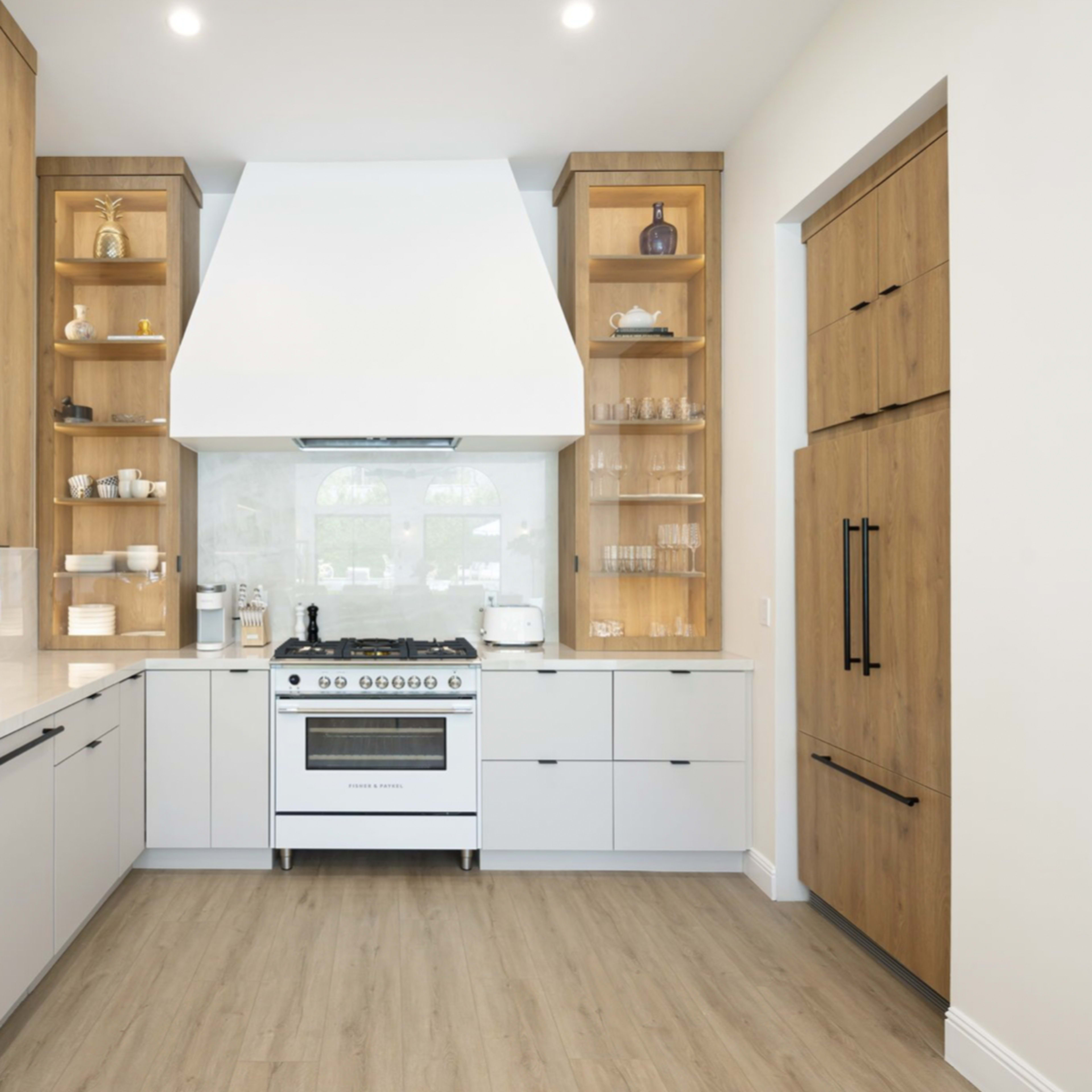 The kitchen features a large central stove with a vent hood, surrounded by wooden shelves and cabinetry in muted colors.