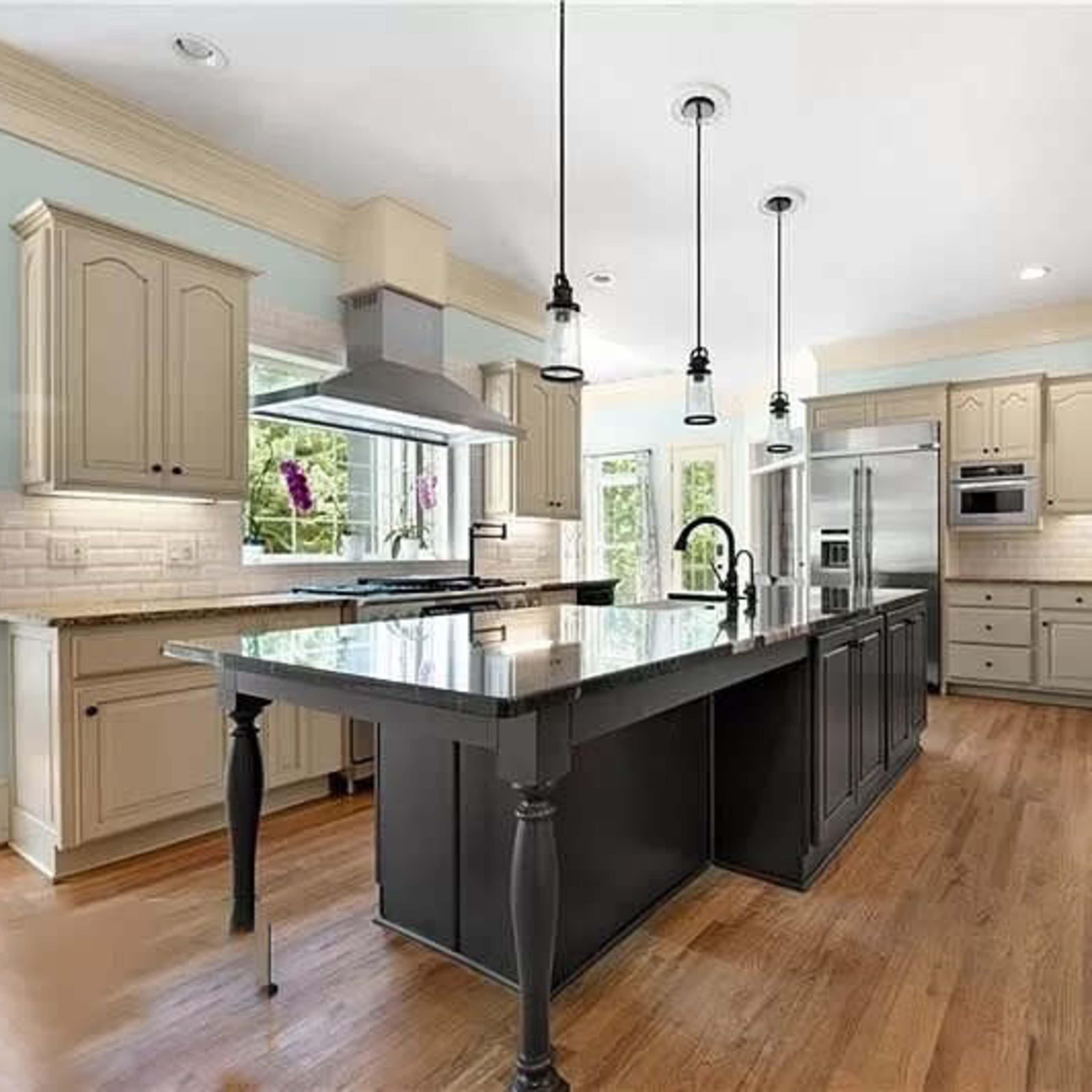 The kitchen features a central island with a dark countertop, surrounded by light-colored cabinetry and modern appliances.