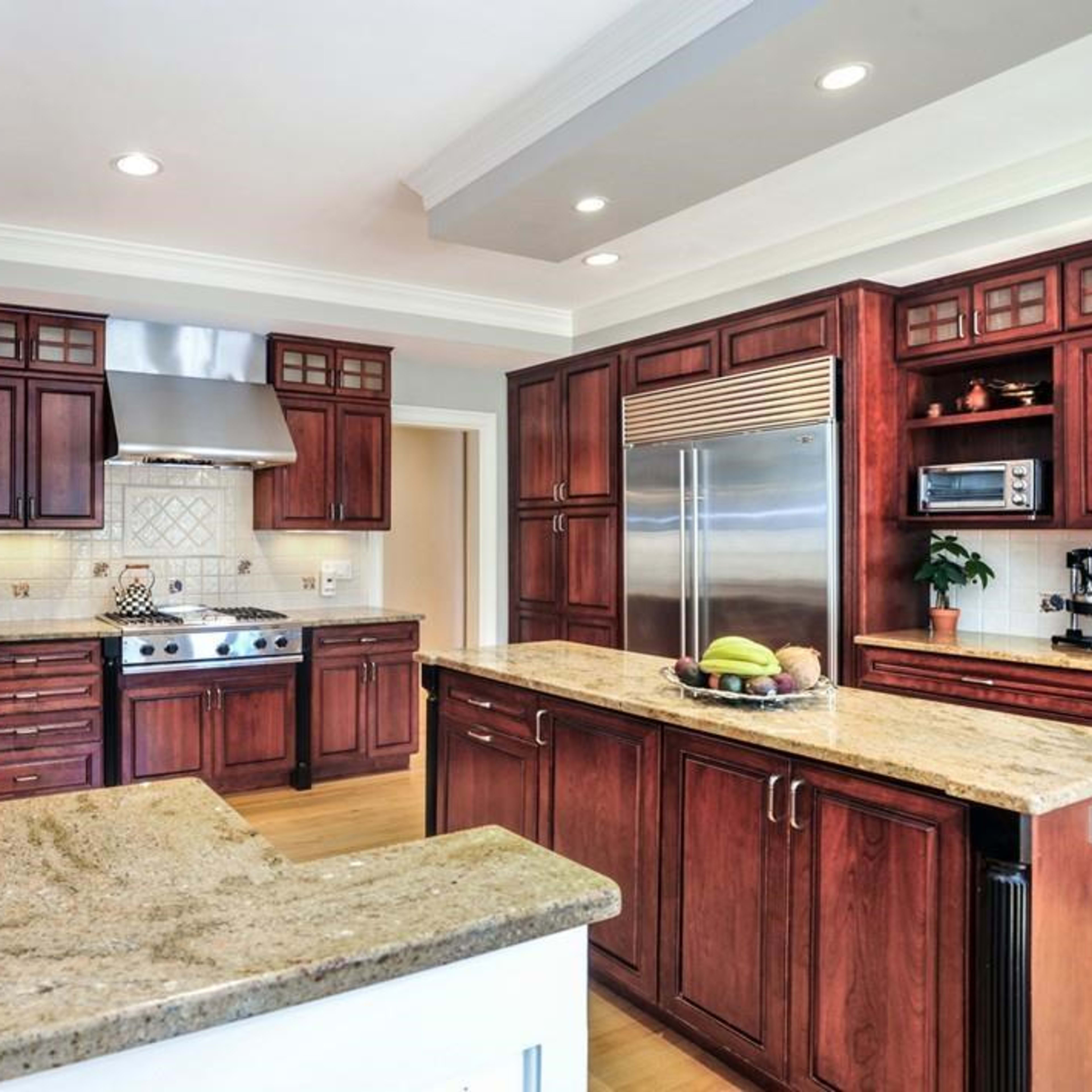 A modern kitchen with dark wood cabinets, granite countertops, and stainless steel appliances.
