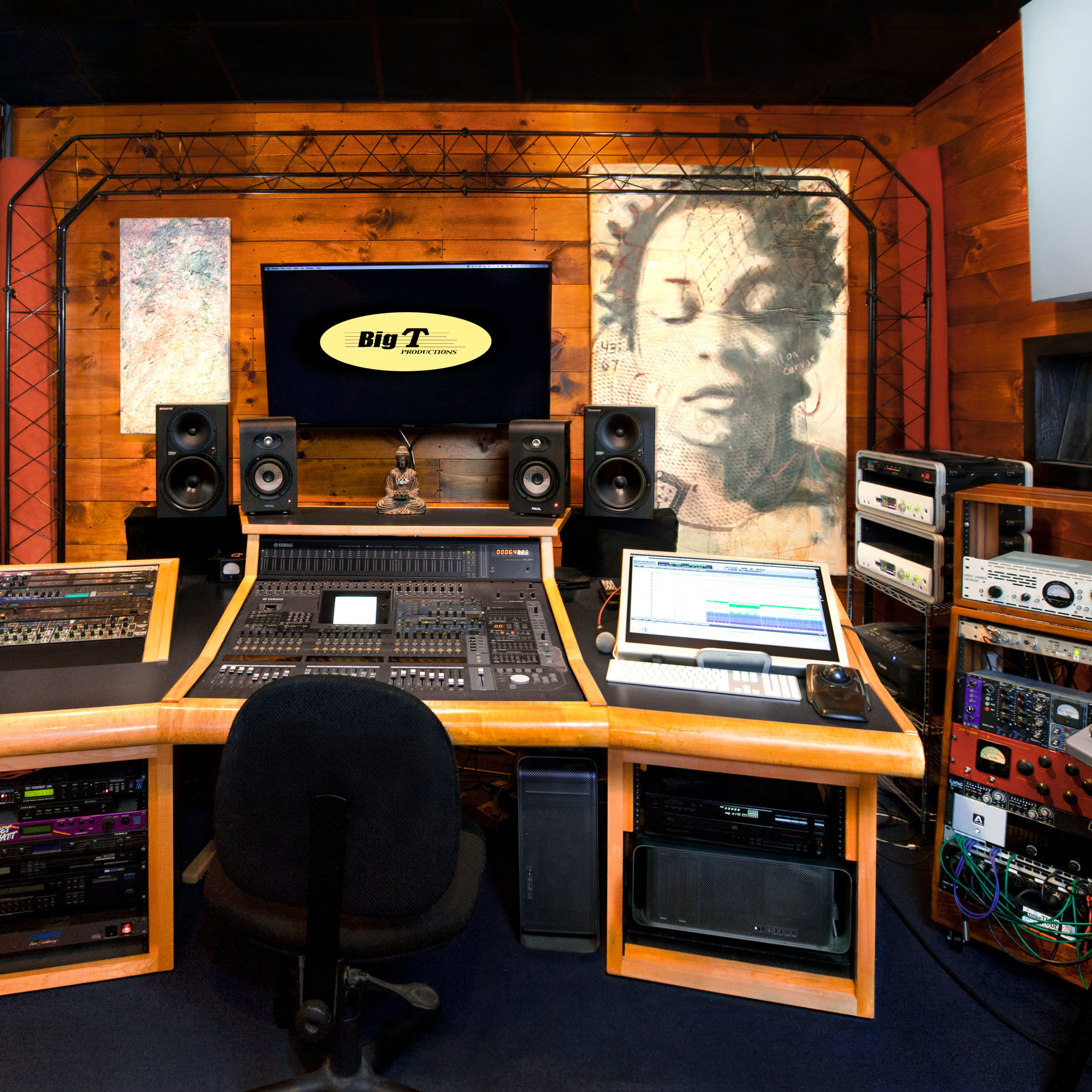 A music recording studio featuring a large mixing console, multiple speakers, and sound equipment arranged around a central workstation.