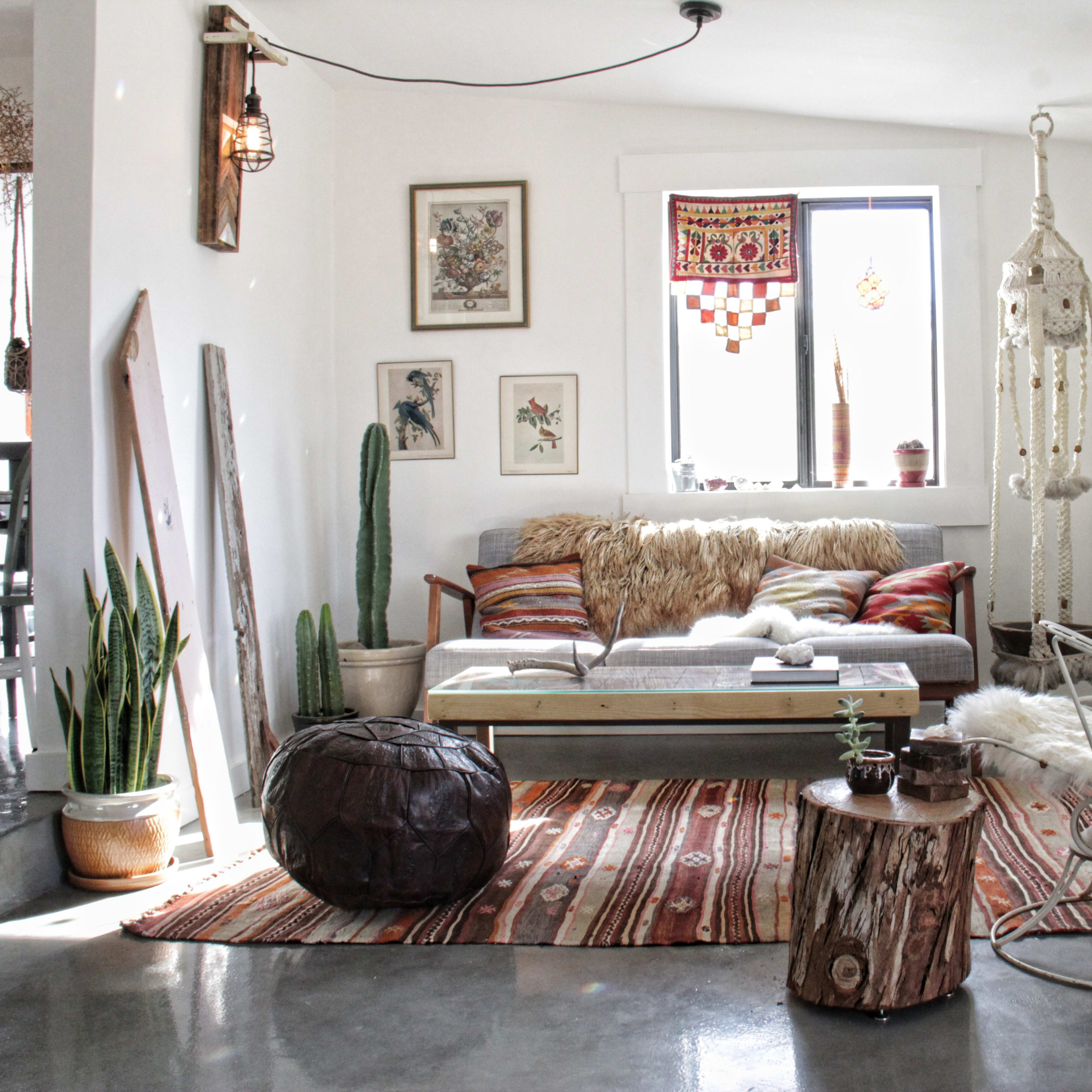A cozy living room with a mid-century style couch, a macramé hanging chair, potted plants, and colorful rugs.