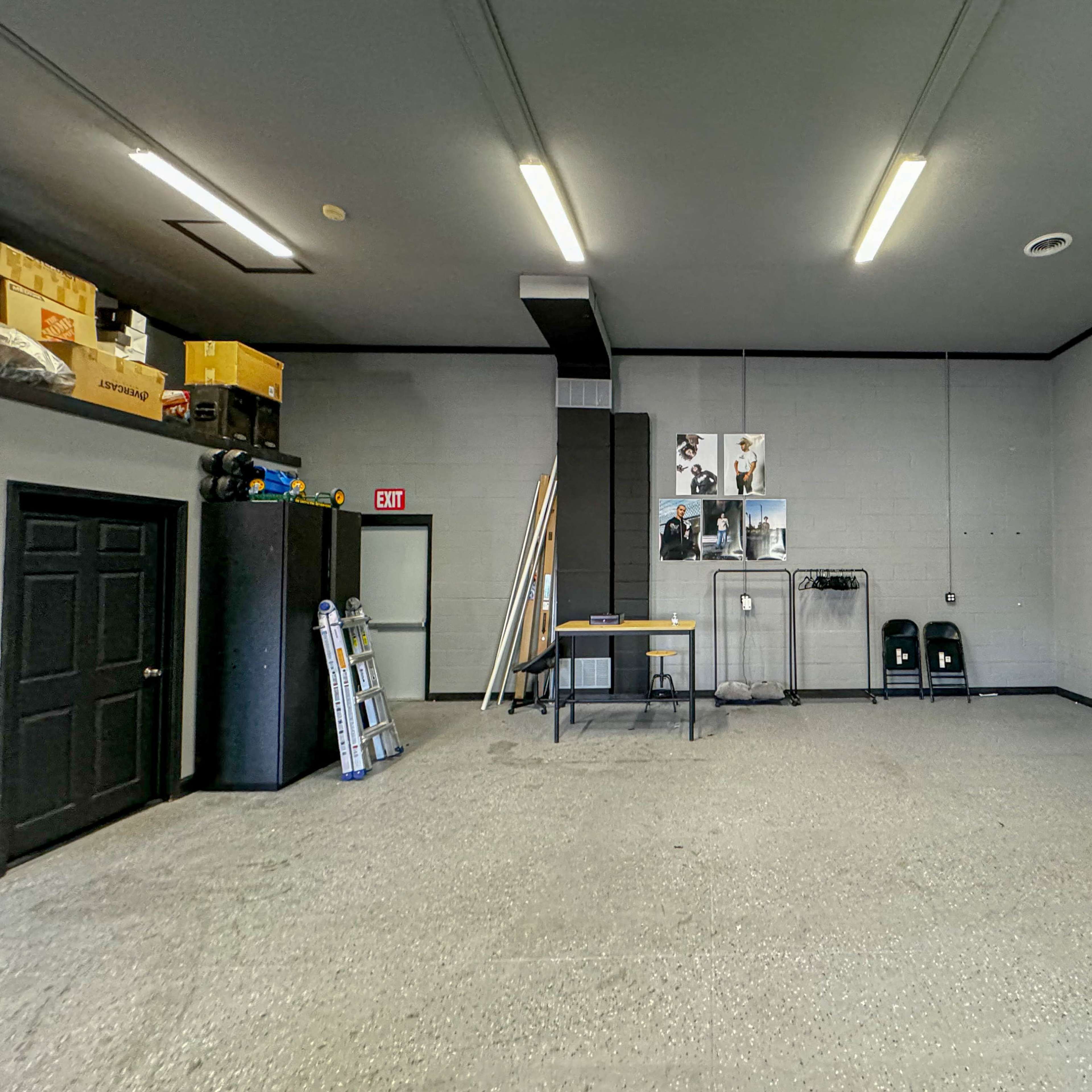 A spacious, empty garage with gray walls, a table in the center, and various storage items along the walls.