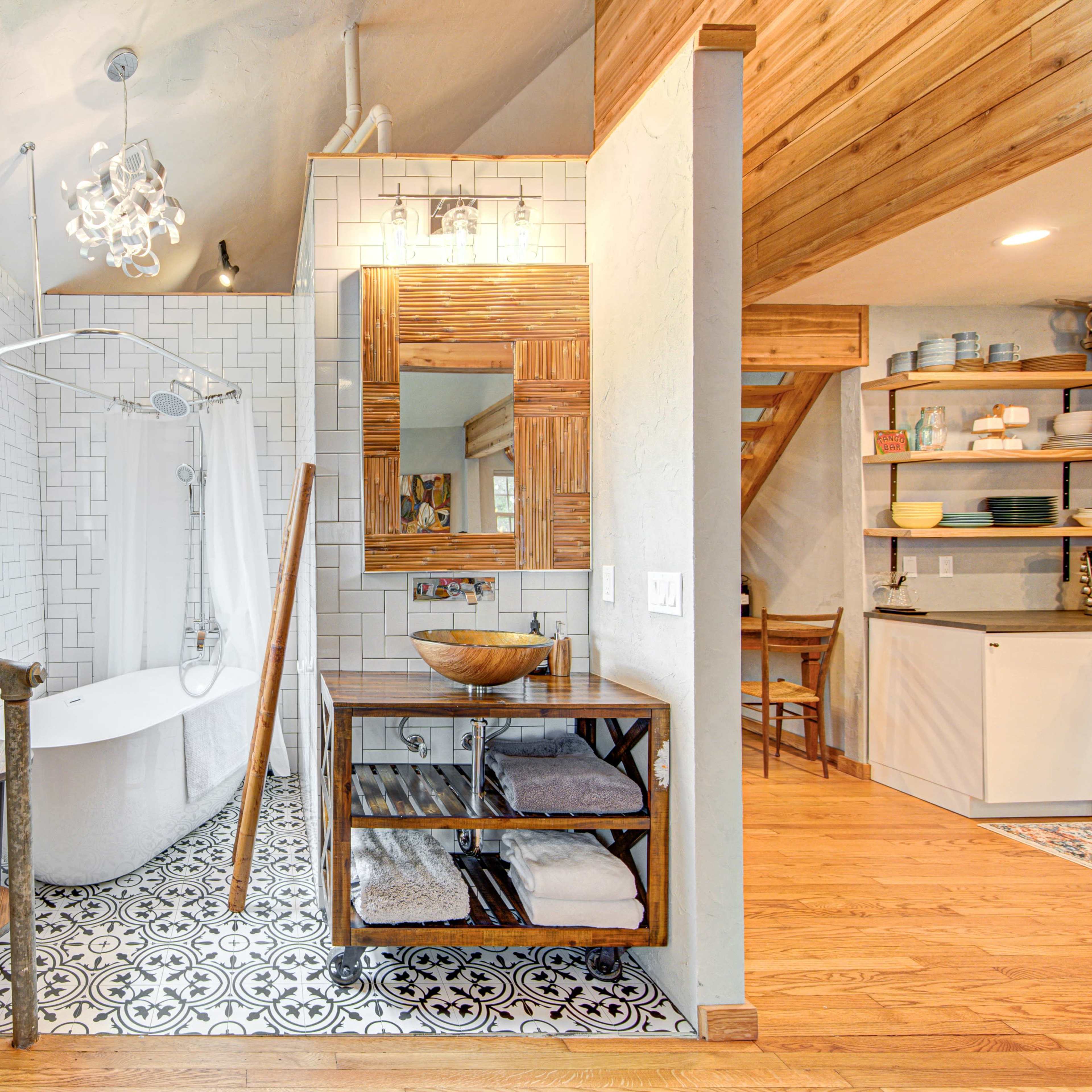 A modern bathroom with a freestanding tub, a rainfall showerhead, a wooden vanity, and patterned floor tiles.