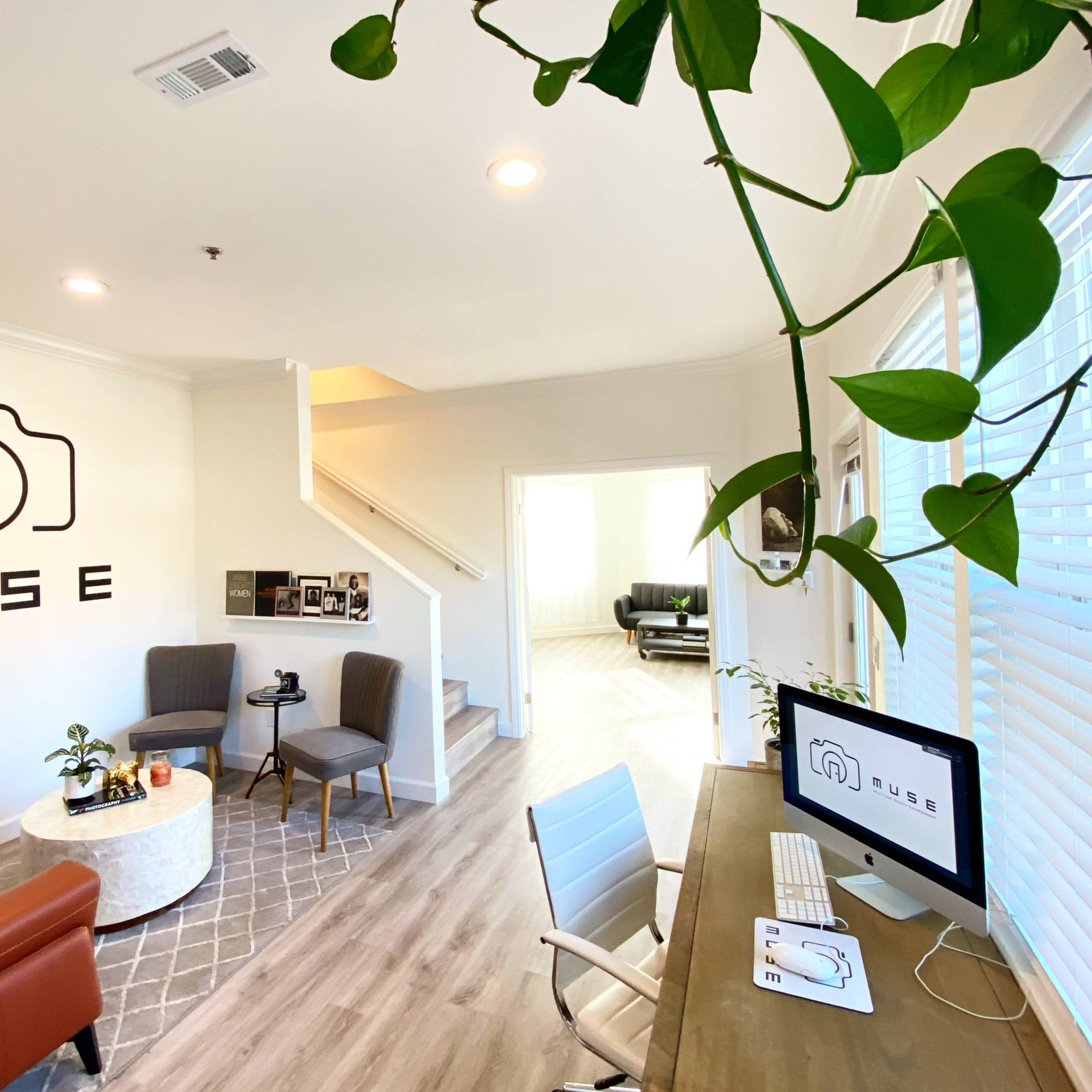 A modern office space with a camera-themed logo on the wall, a seating area, and a desk equipped with a computer.