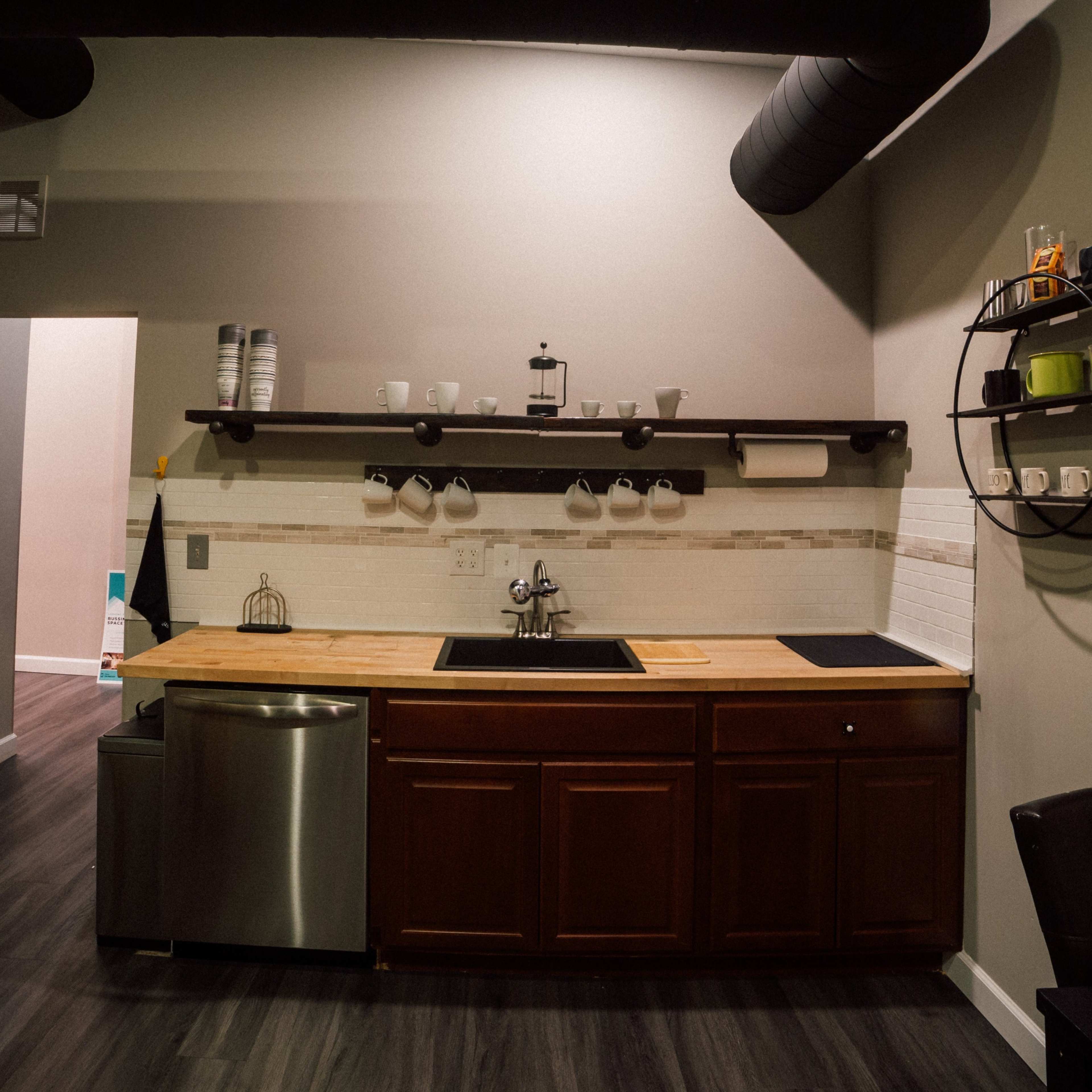 A modern kitchen area with a wooden countertop, stainless steel sink, and minimal decor.