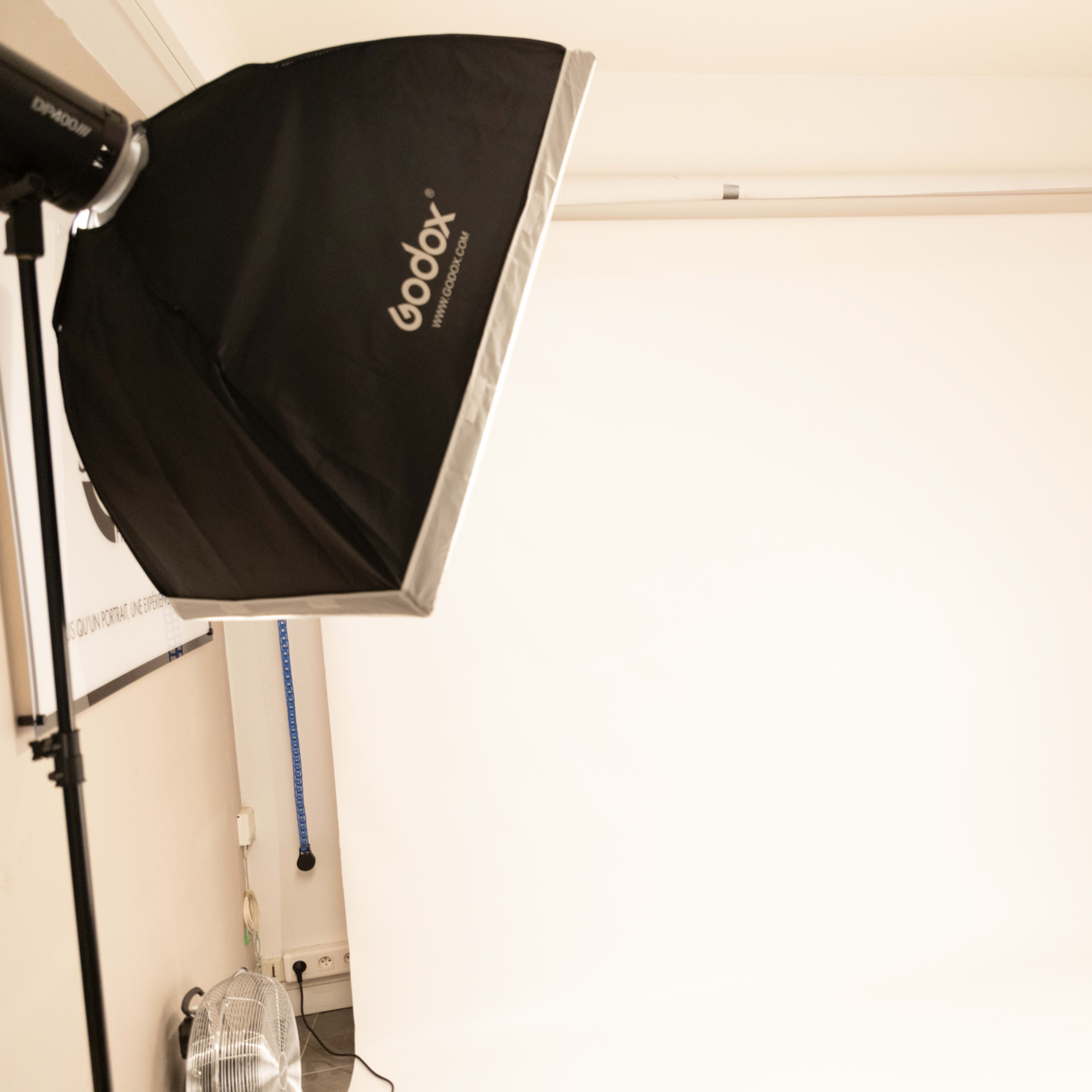 A photography studio with two Godox light setups and a plain white backdrop.