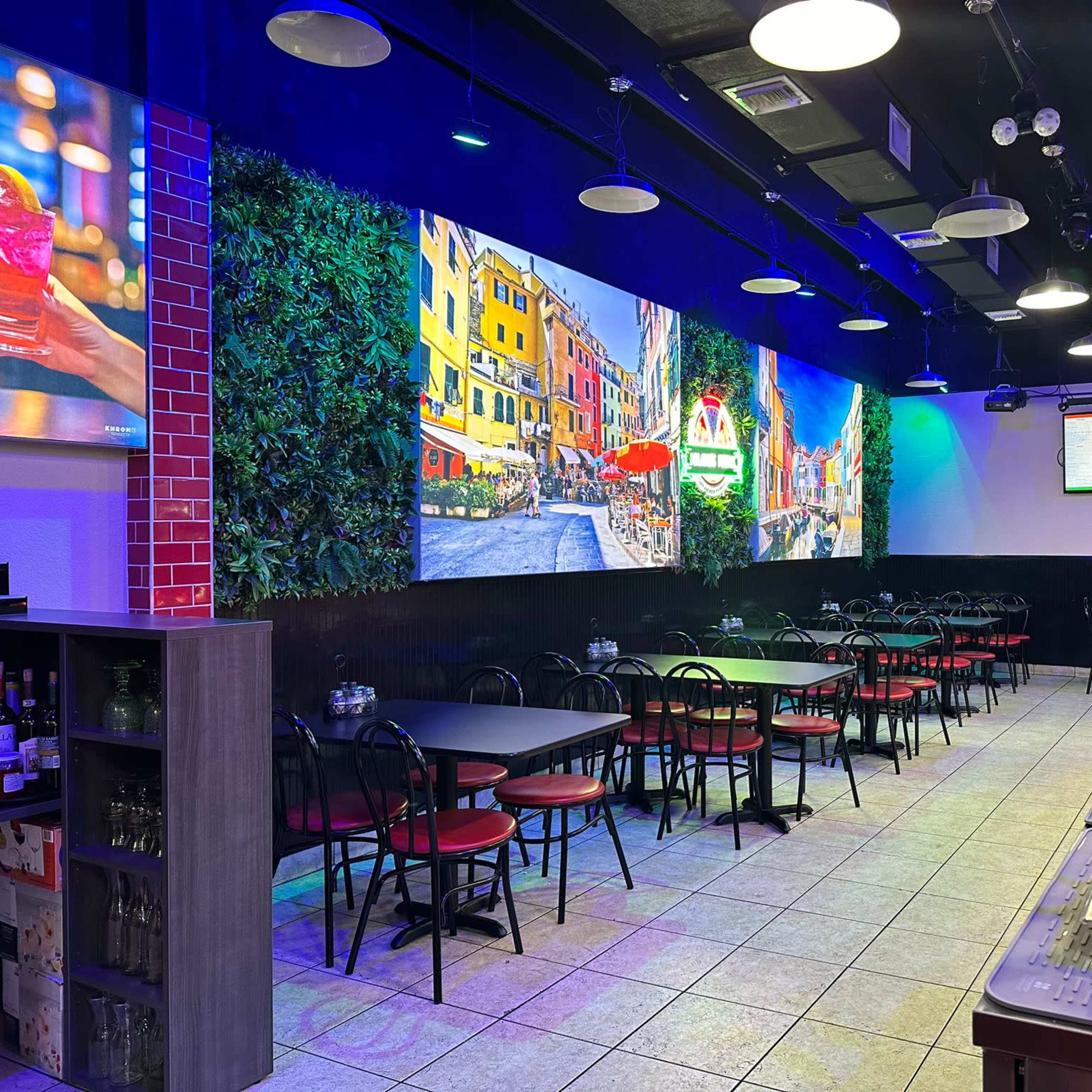 A restaurant interior with tables and chairs arranged beneath a colorful mural depicting a scenic street.