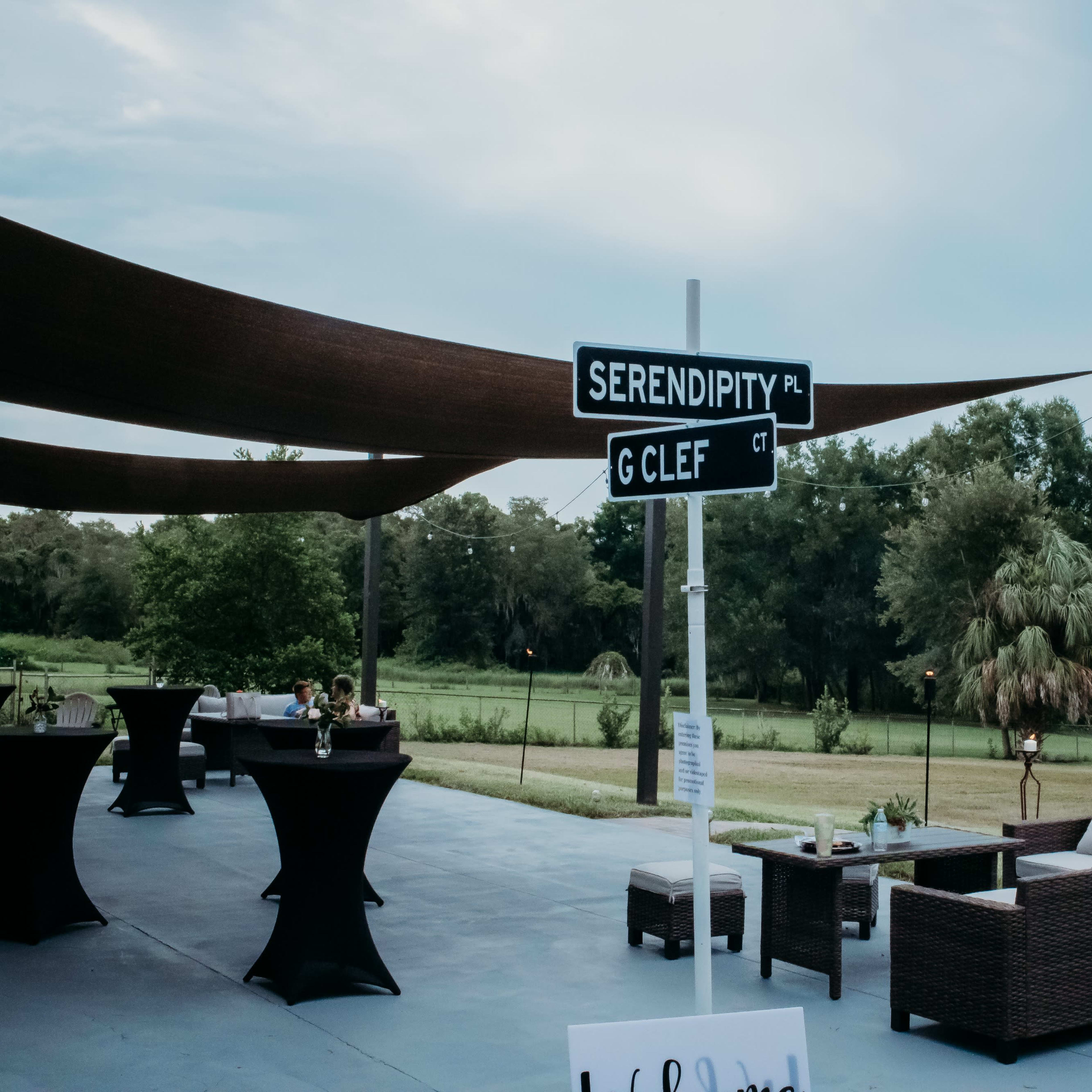 A signpost displays "SERENDIPITY PL" and "CLEF CT" next to an outdoor seating area under a shaded structure.