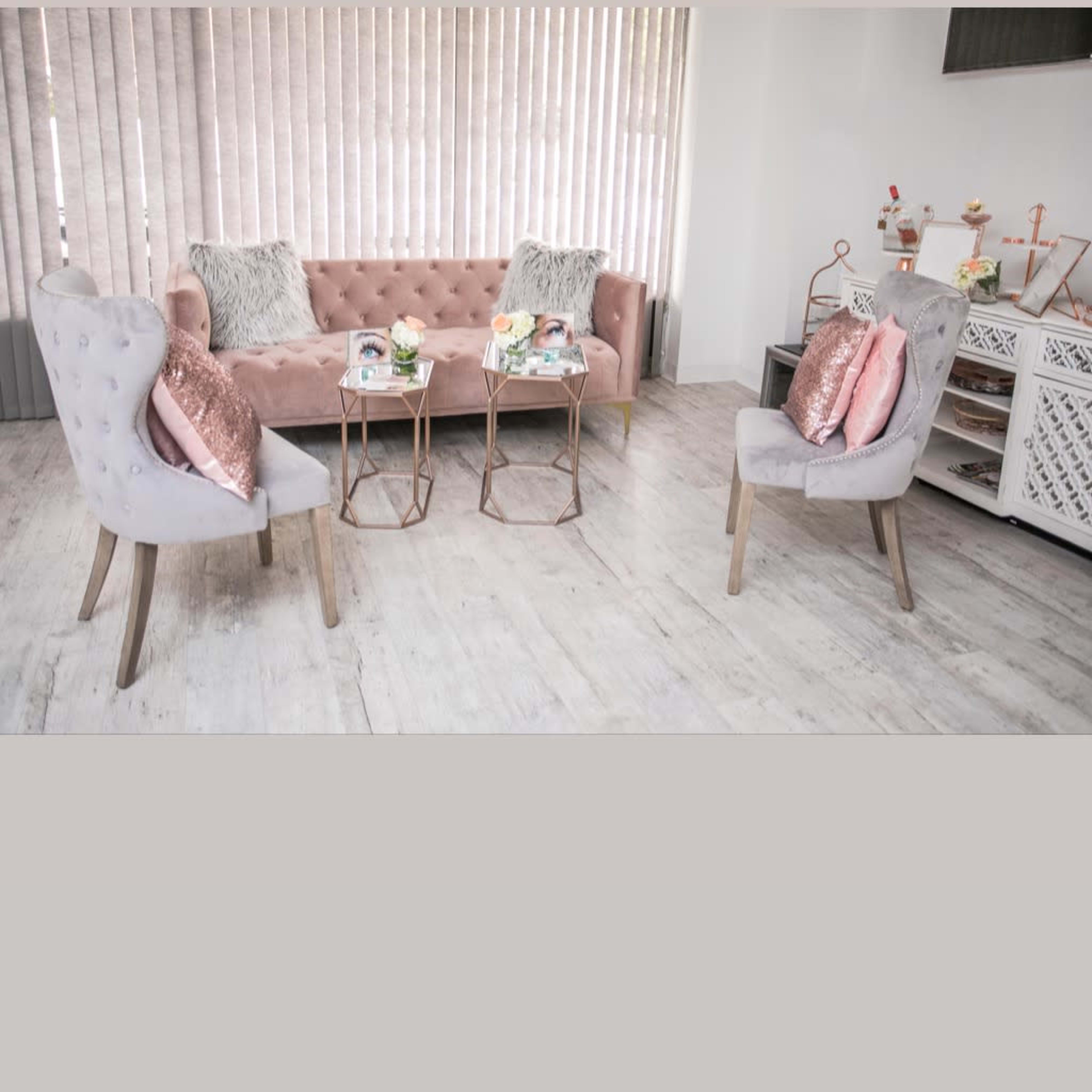 A modern, elegantly furnished sitting area with a pink tufted sofa and two matching armchairs arranged around small side tables.
