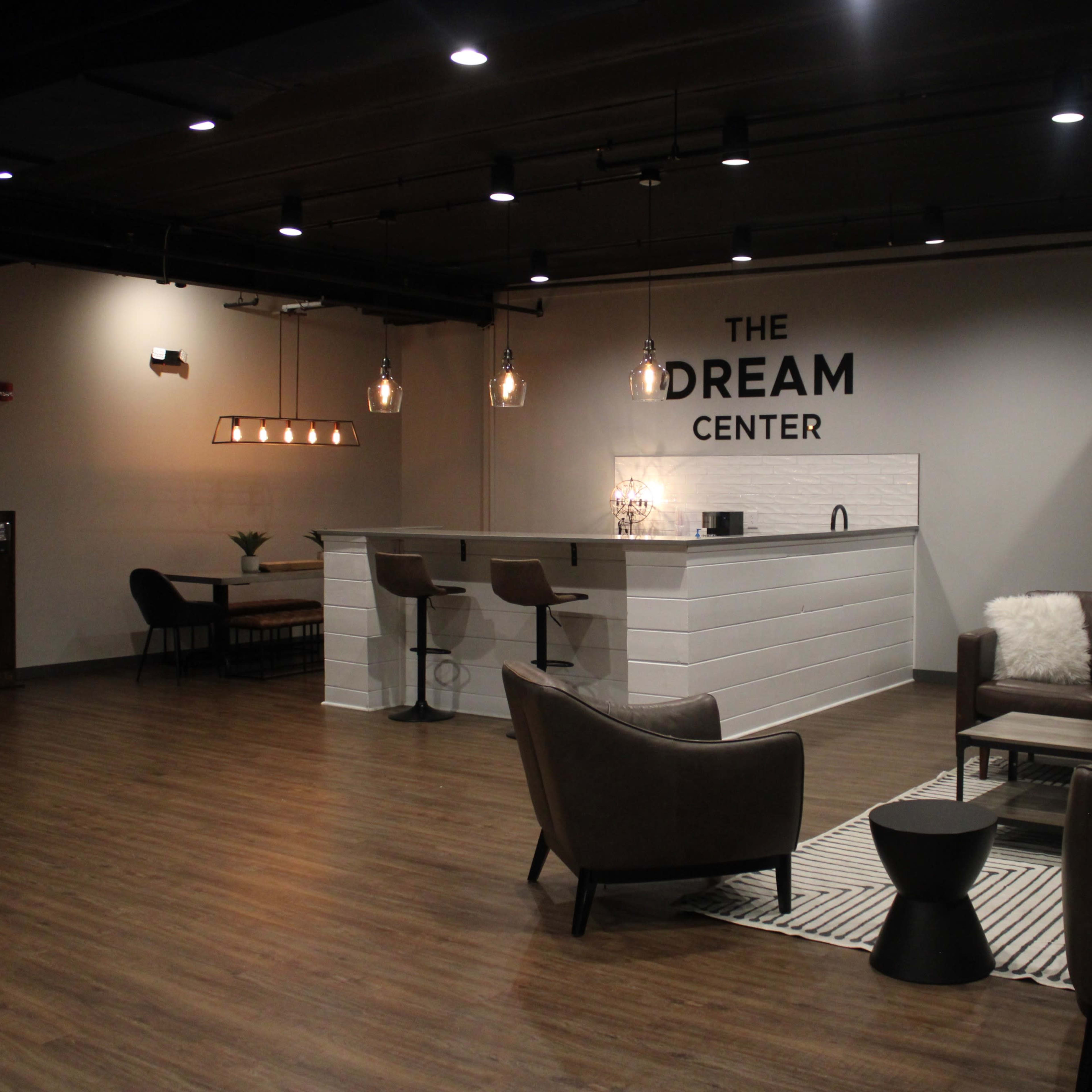 A modern interior space featuring a bar area with stools, seating arrangements, and decorative lighting.
