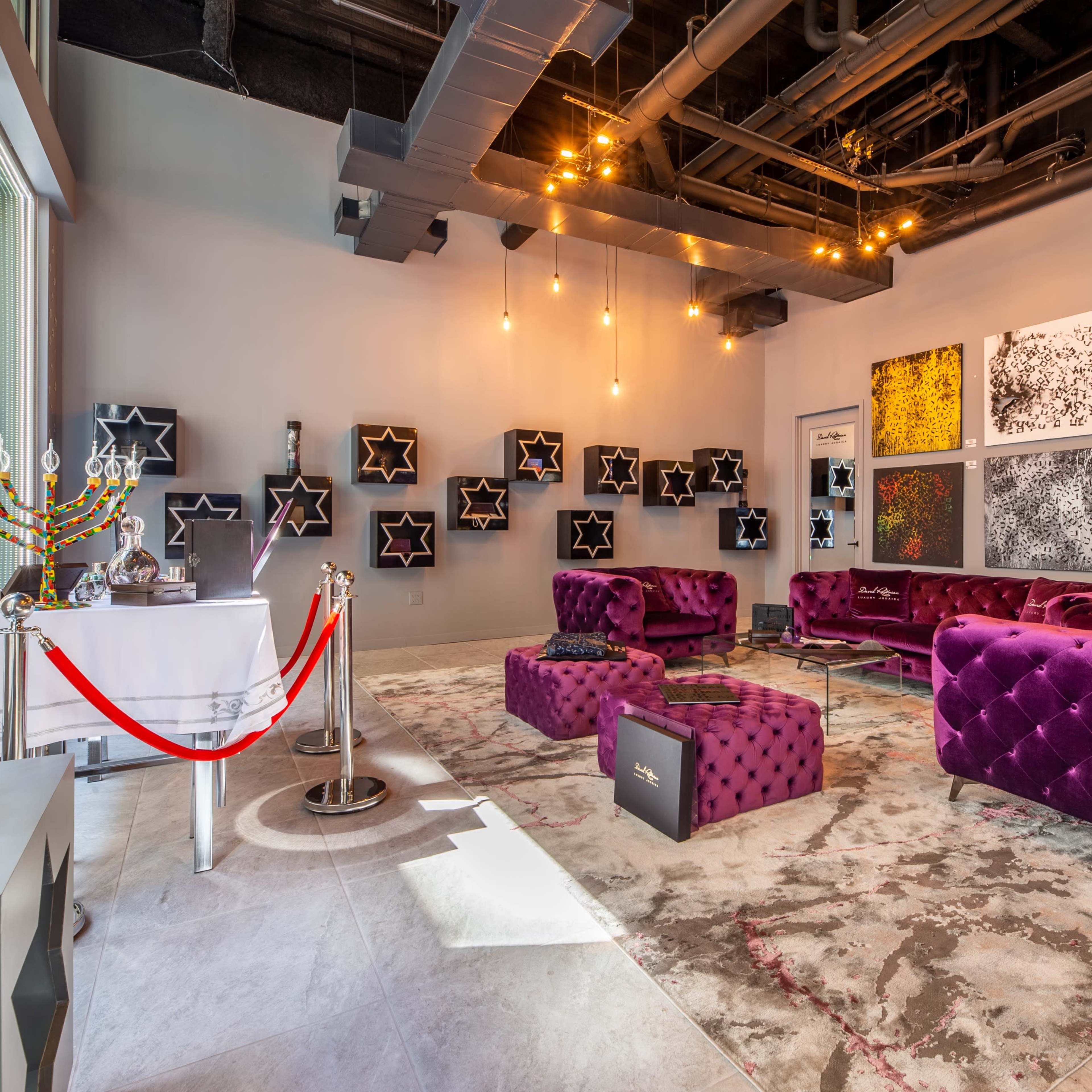 The scene shows a modern interior with purple velvet seating, artwork on the walls, and a display area featuring various products.
