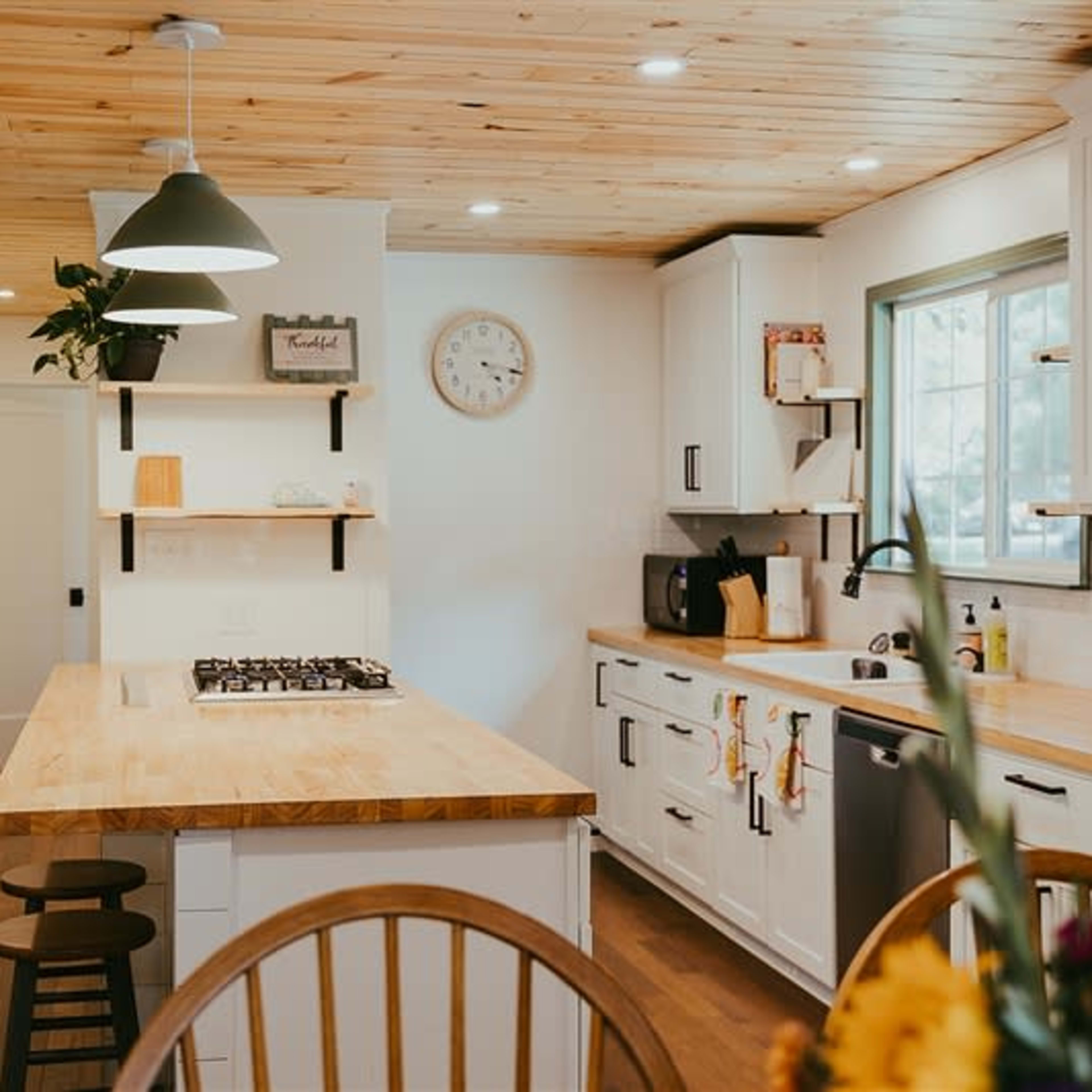 A modern kitchen with a wooden island, white cabinetry, and a window above the sink.