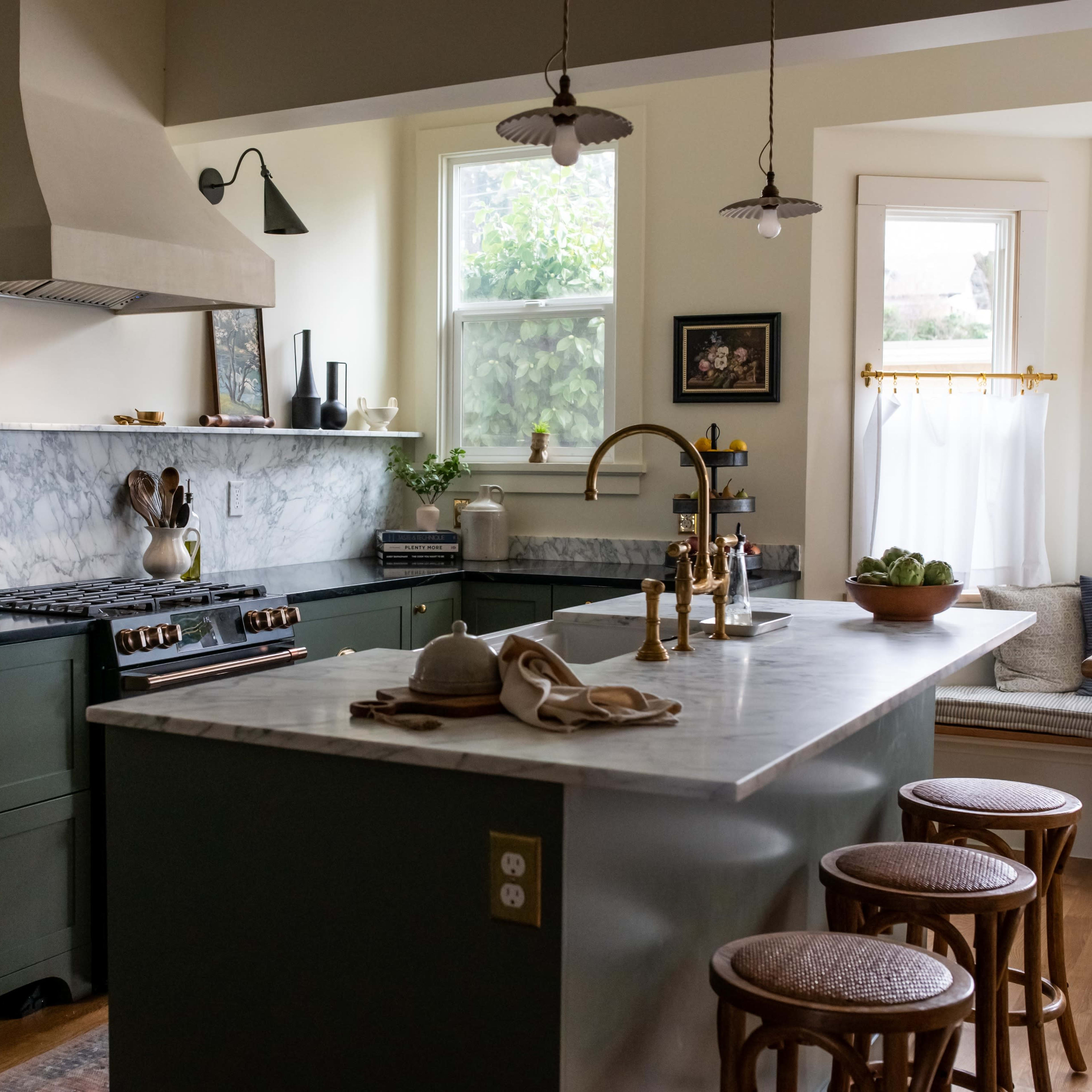 The kitchen features a marble countertop, green cabinetry, a large stove, and a window seat with natural light.