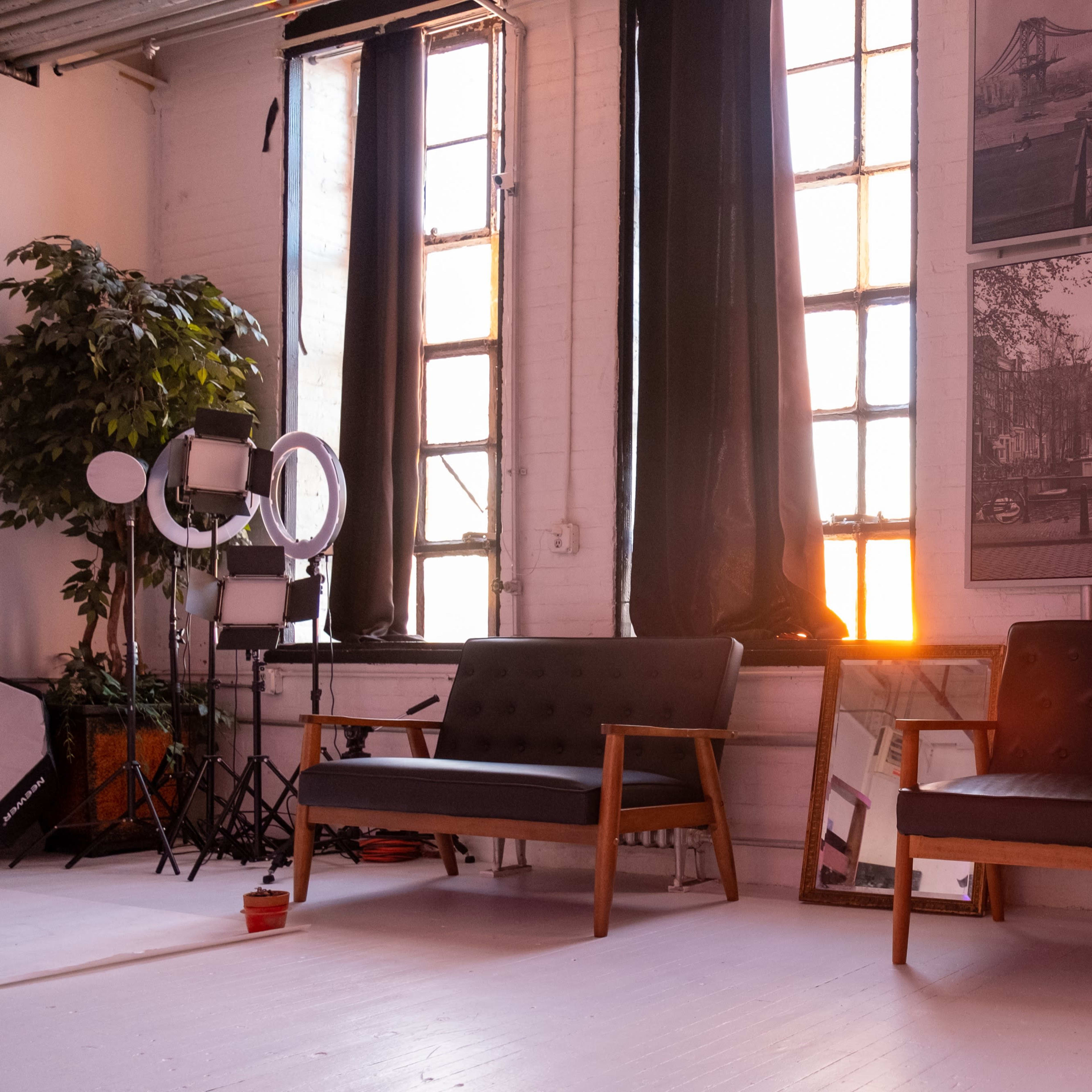 A sunlit room with two mid-century modern sofas, large windows, and a wall featuring black-and-white photographs.