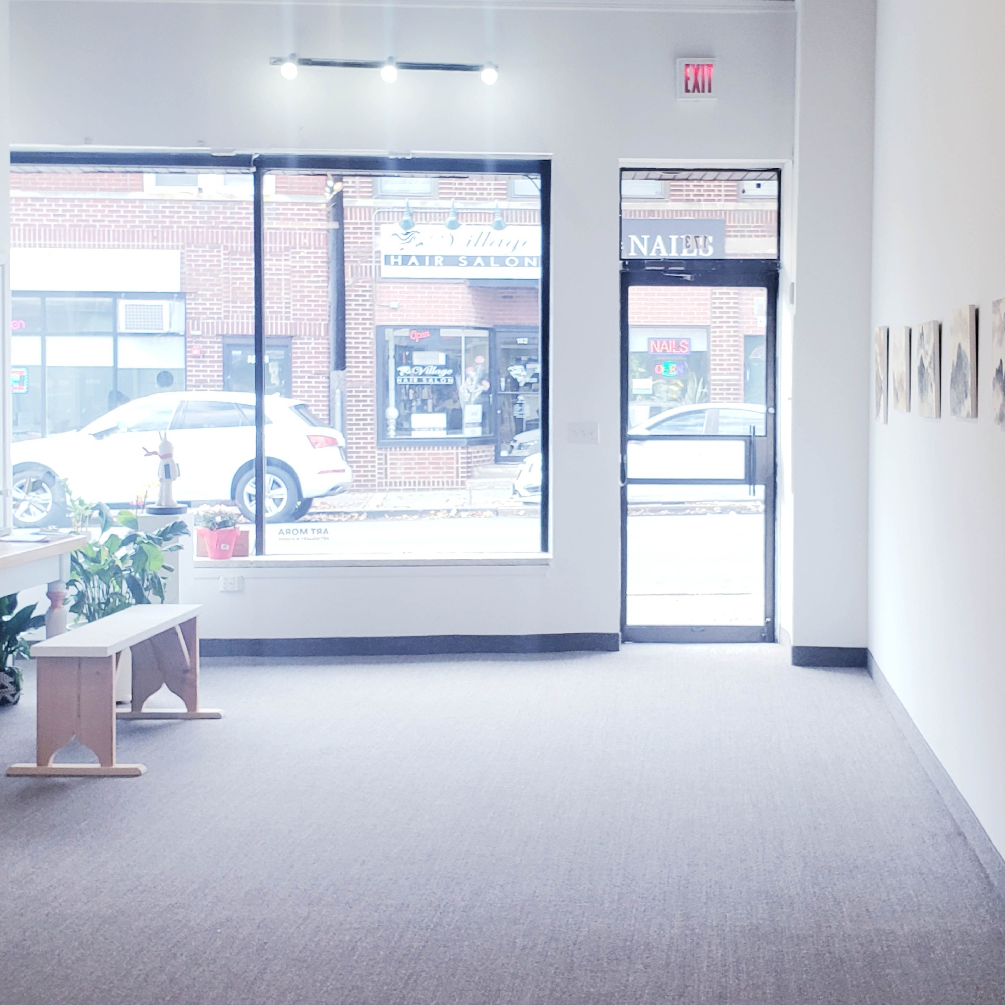 A spacious art gallery features a series of black-and-white artworks displayed on the walls, with a bench and a small table positioned in the center.