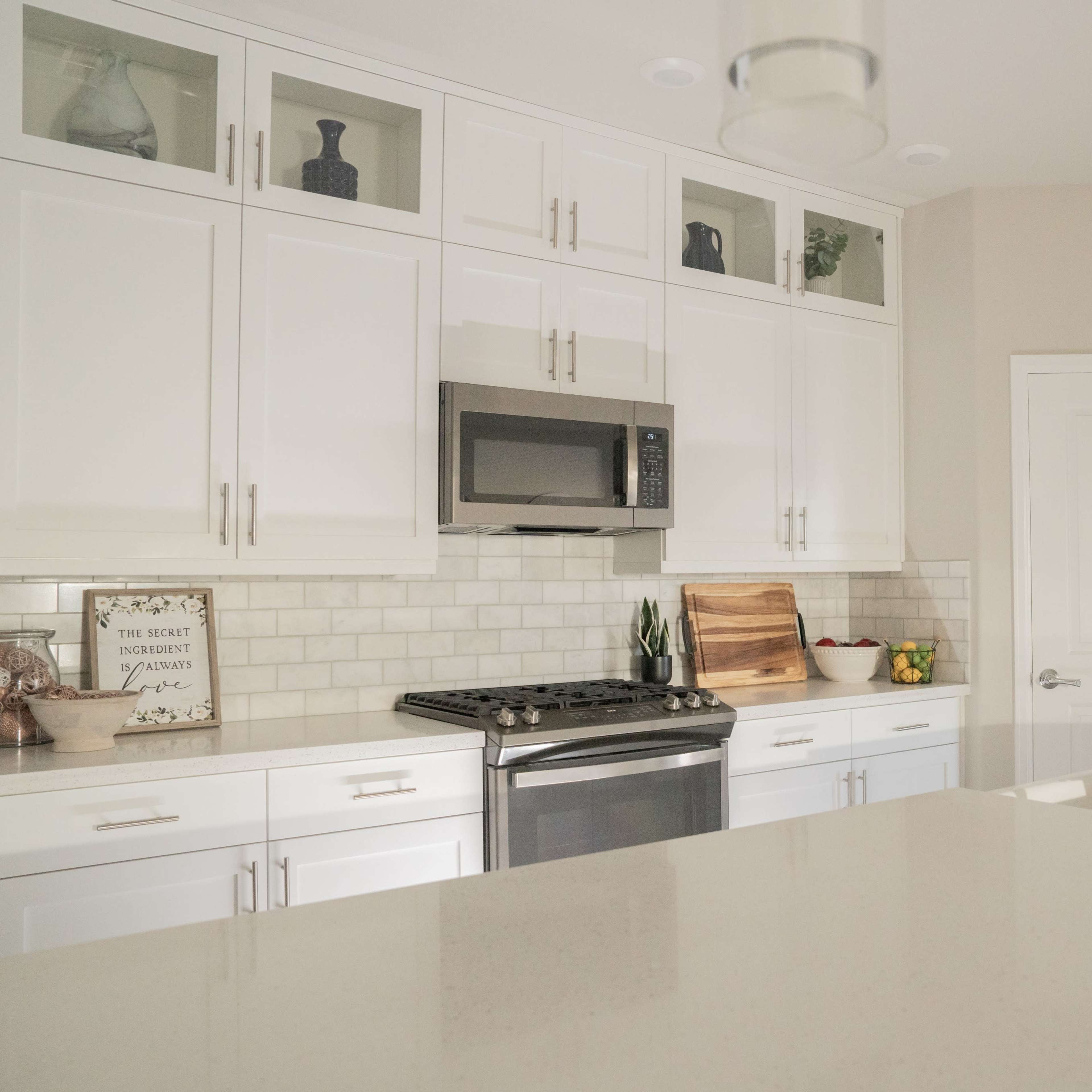 A modern kitchen featuring white cabinetry, stainless steel appliances, and a marble countertop.