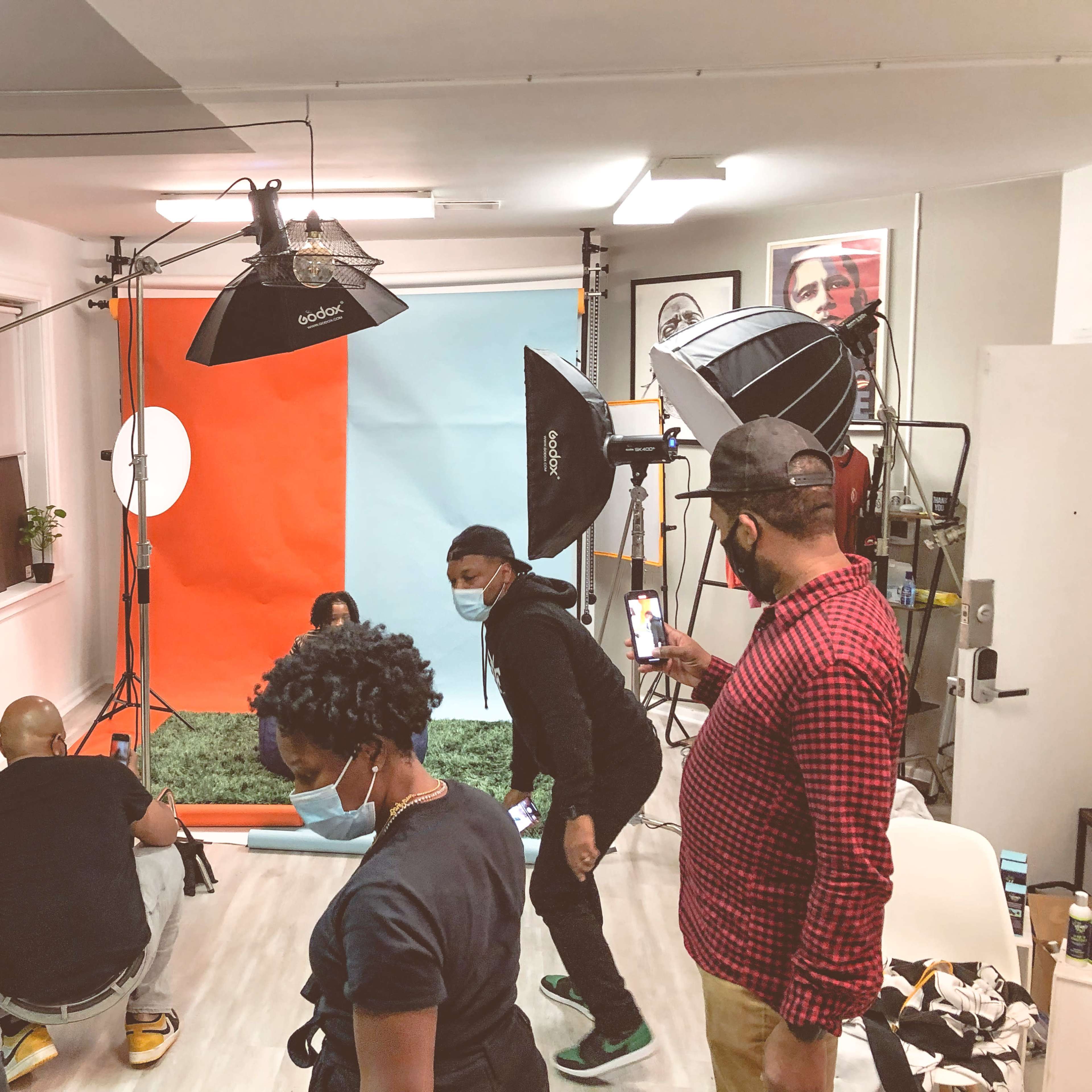 A group of individuals set up a photoshoot in a studio with a colorful backdrop and multiple lighting equipment.