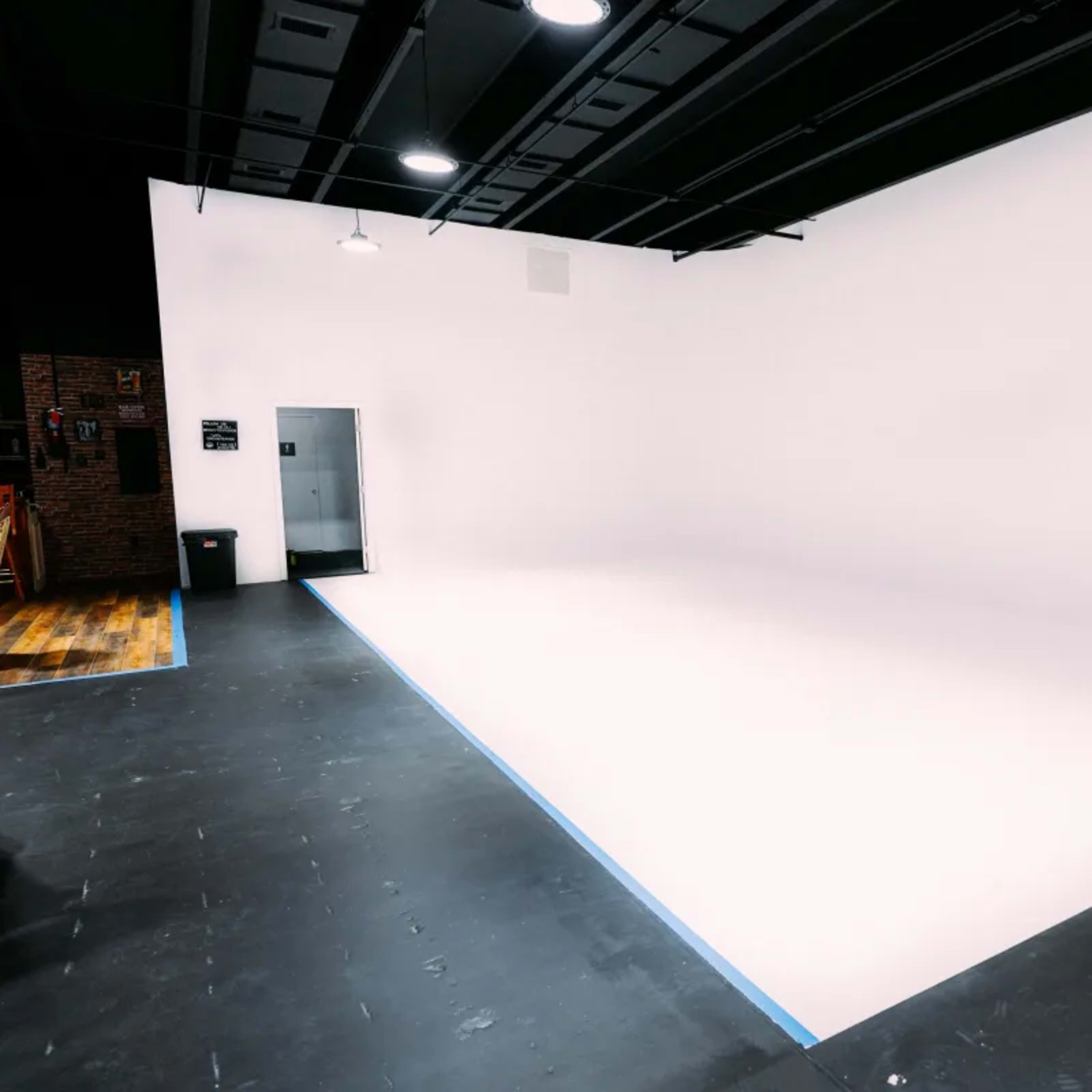 An empty studio space featuring a seamless white backdrop and a black floor.