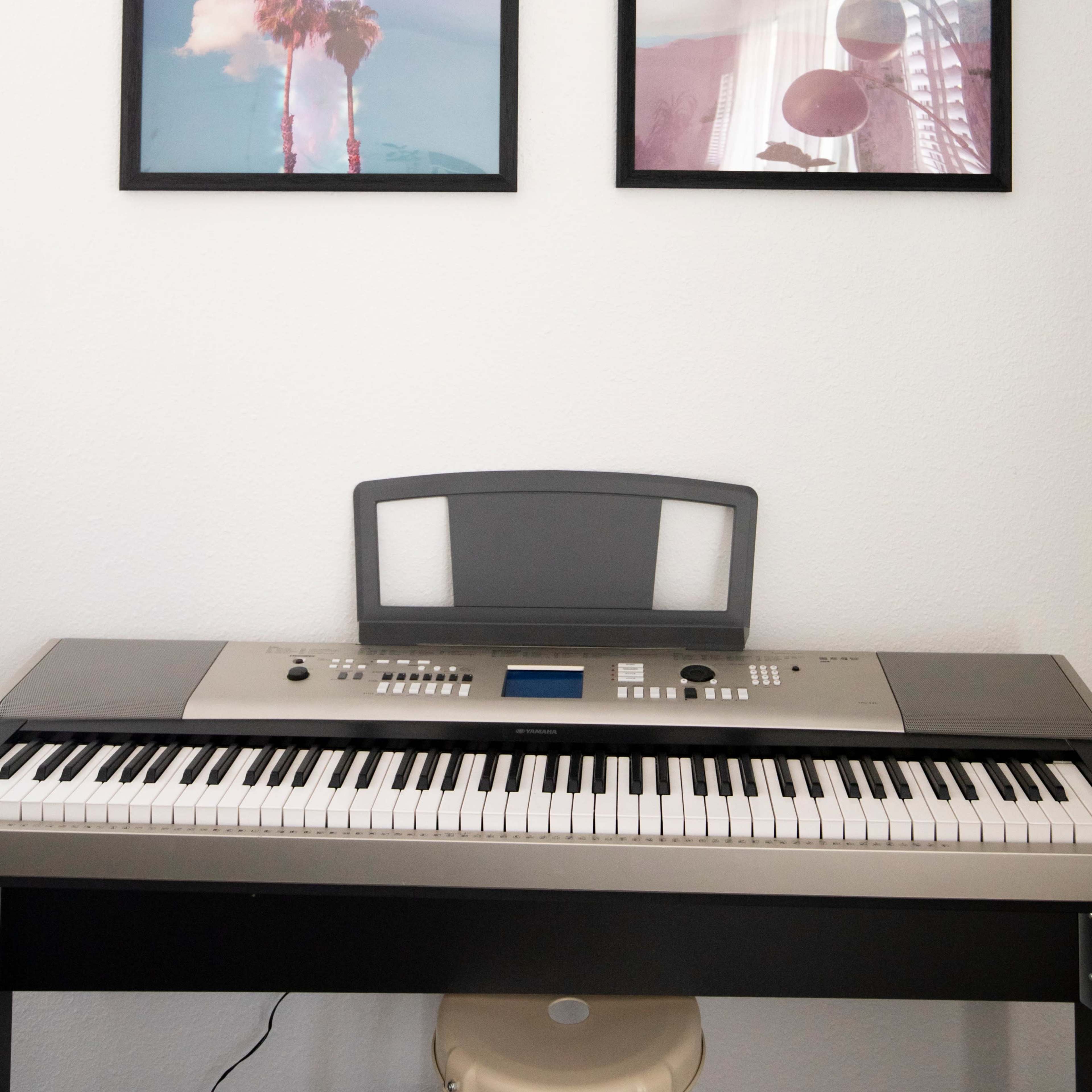 A keyboard sits beneath two framed photographs of palm trees and abstract reflections on a wall.