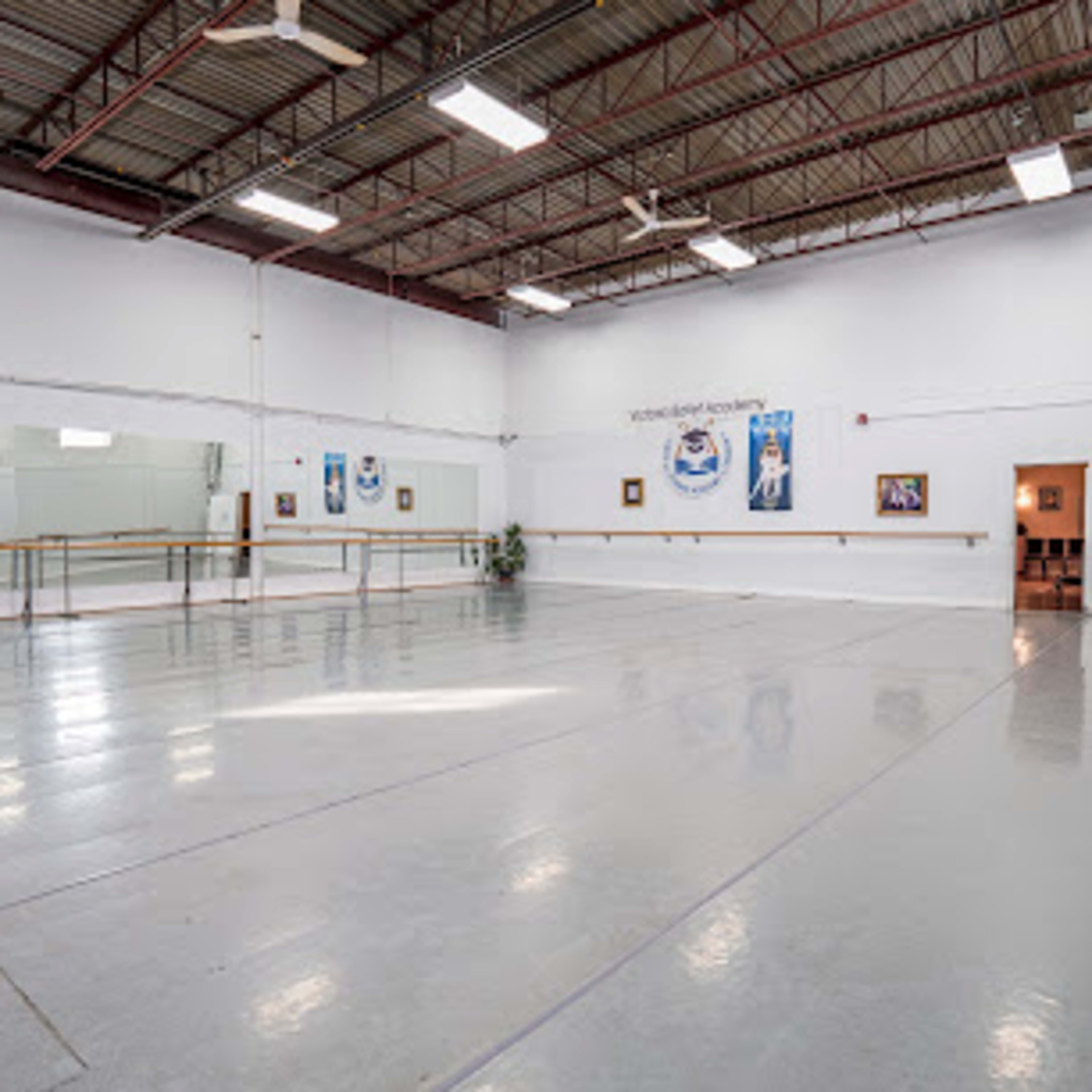 A spacious dance studio with mirrors along one wall, polished concrete floors, and a few framed artworks.