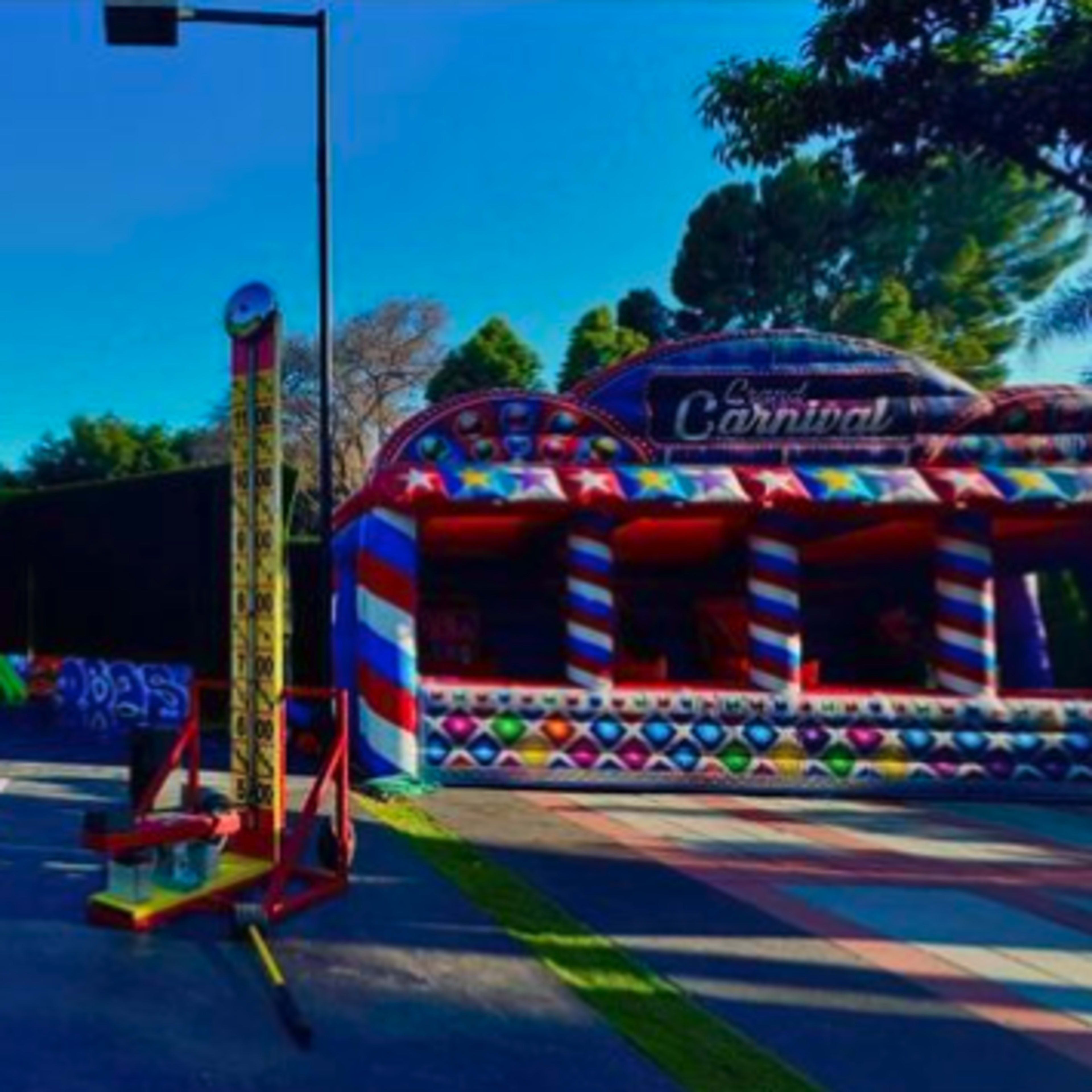 A vibrant outdoor activity area featuring a colorful court, a carnival-style booth, and a basketball hoop.