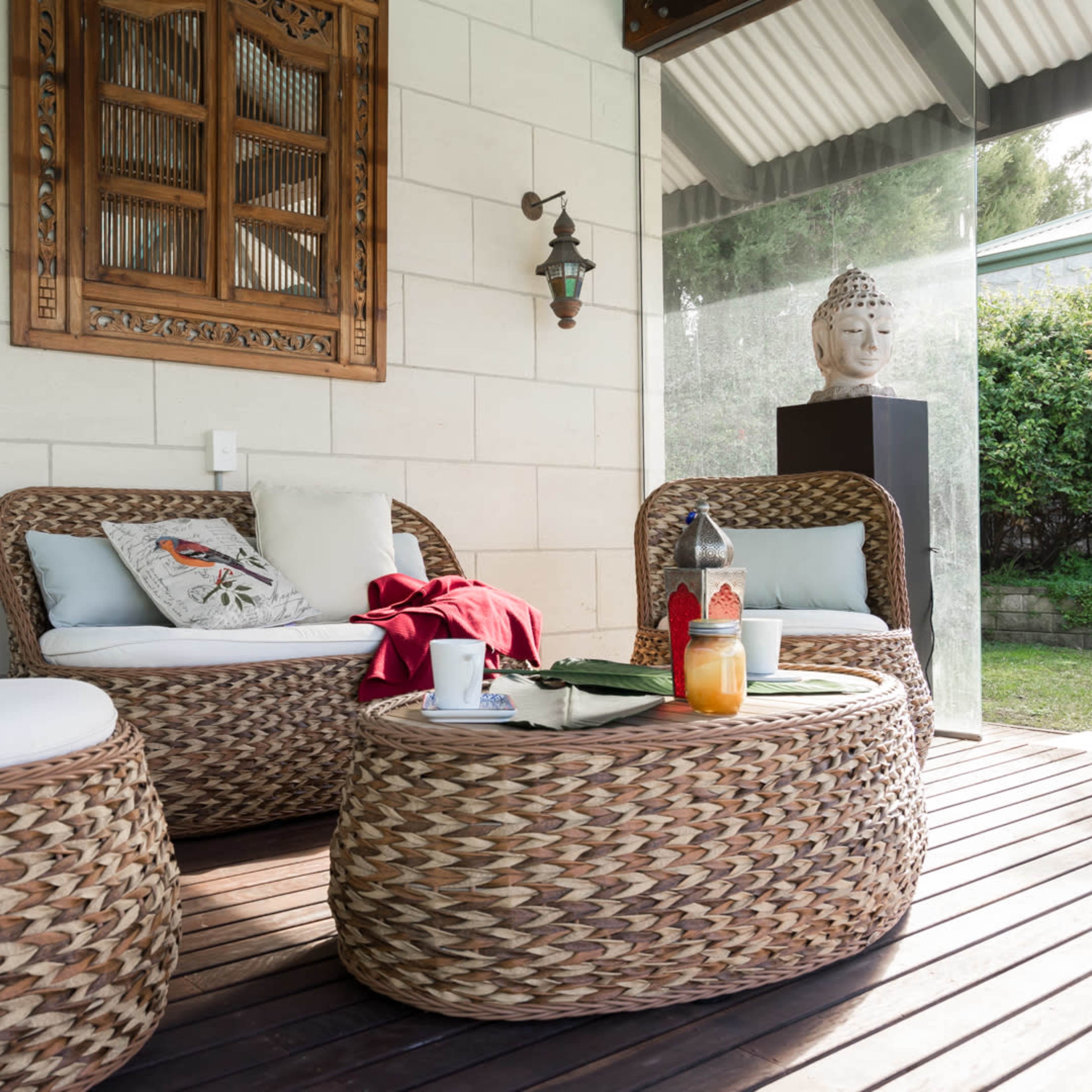 A cozy outdoor seating area featuring woven furniture and a decorative wooden wall hanging.