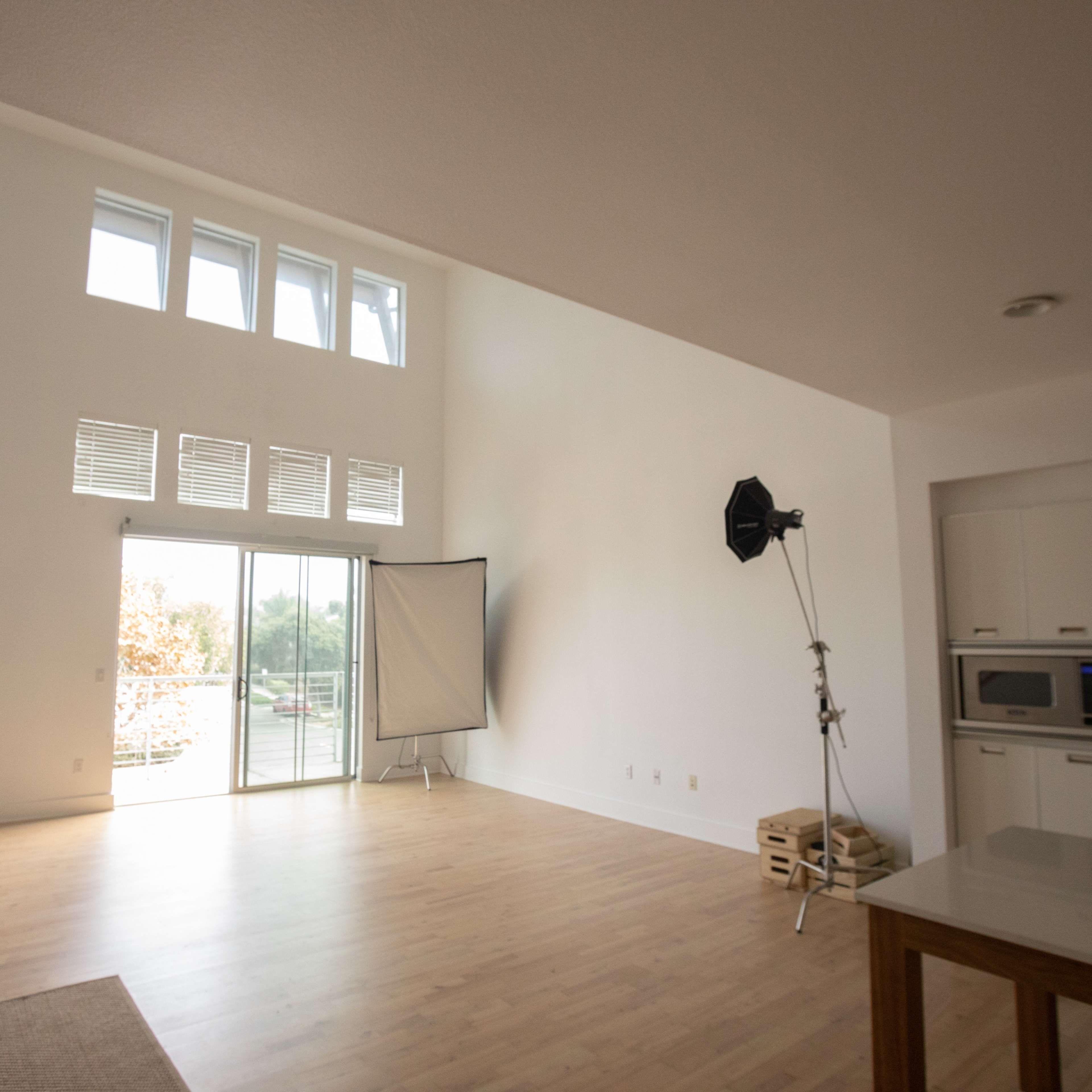 A spacious, modern living area with large windows, neutral walls, and a sliding glass door leading to an outdoor space.