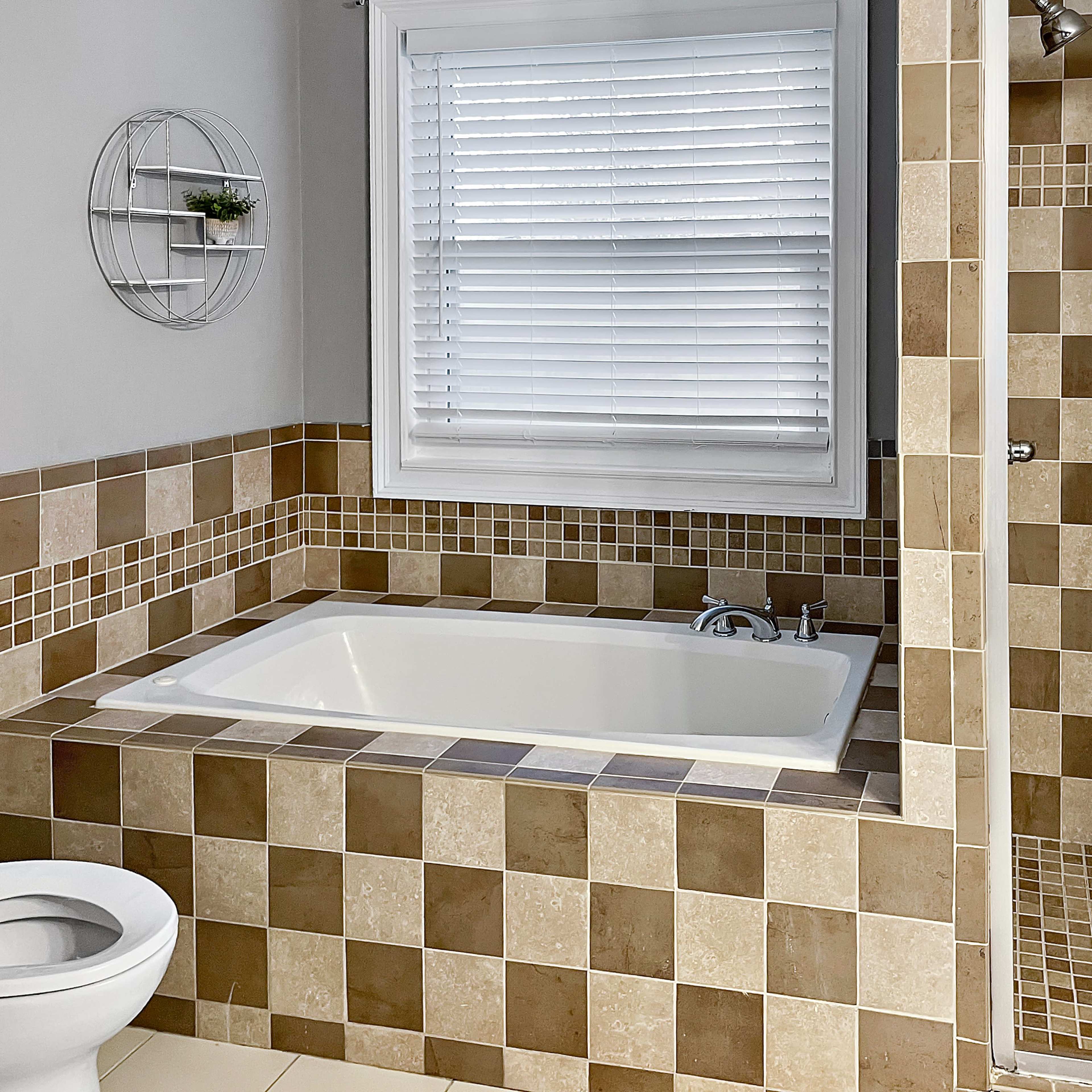 A bathroom featuring a bathtub, a separate glass shower, and tiled walls in brown and beige tones.
