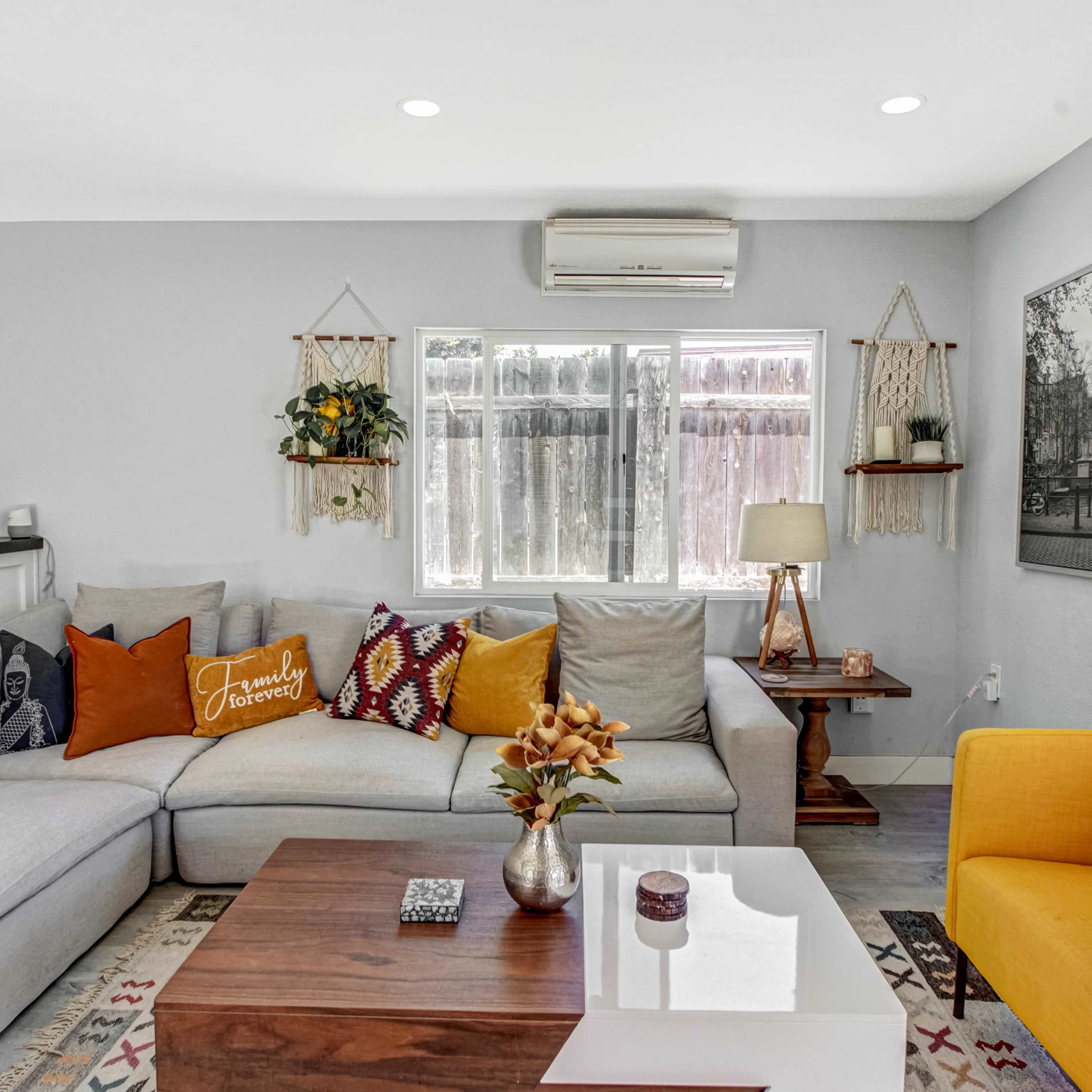 The living room features a gray sectional sofa, a wooden coffee table, and a yellow armchair, with decorative pillows and wall art in a cozy arrangement.