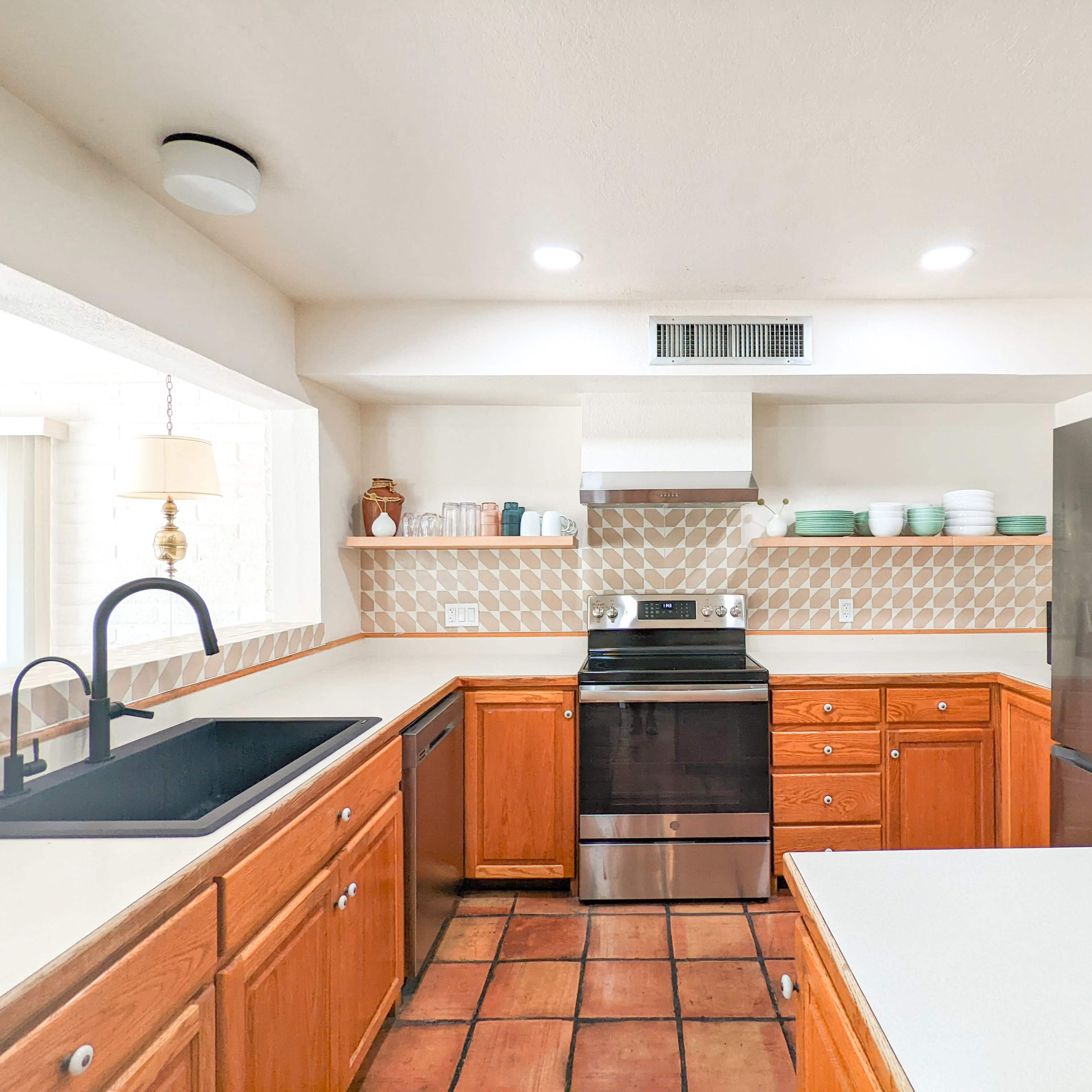 The kitchen features wooden cabinets, a black stove, a modern refrigerator, and a countertop with a patterned backsplash.