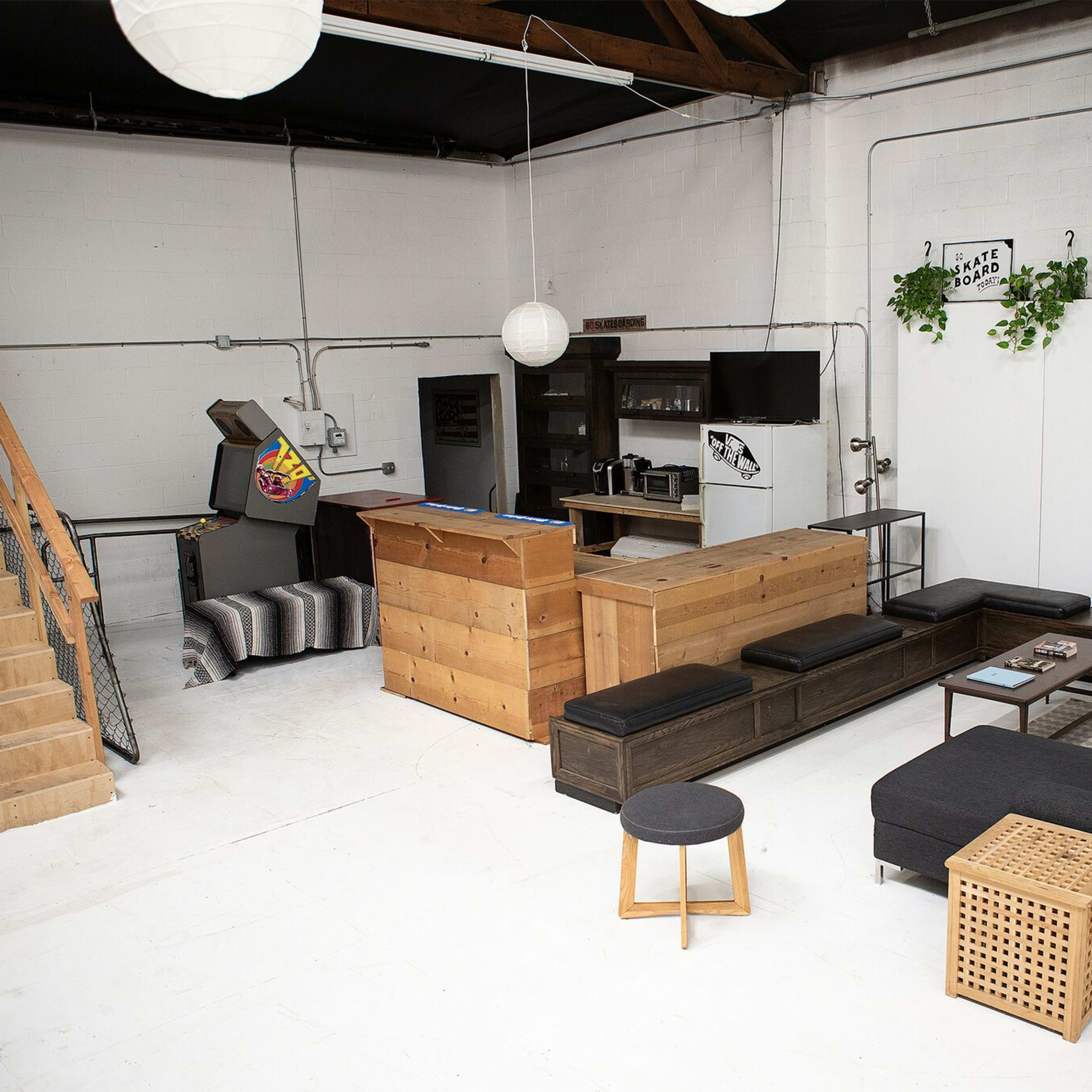 A modern, open-space interior with a wooden bar, seating area, and a staircase leading to a second level.