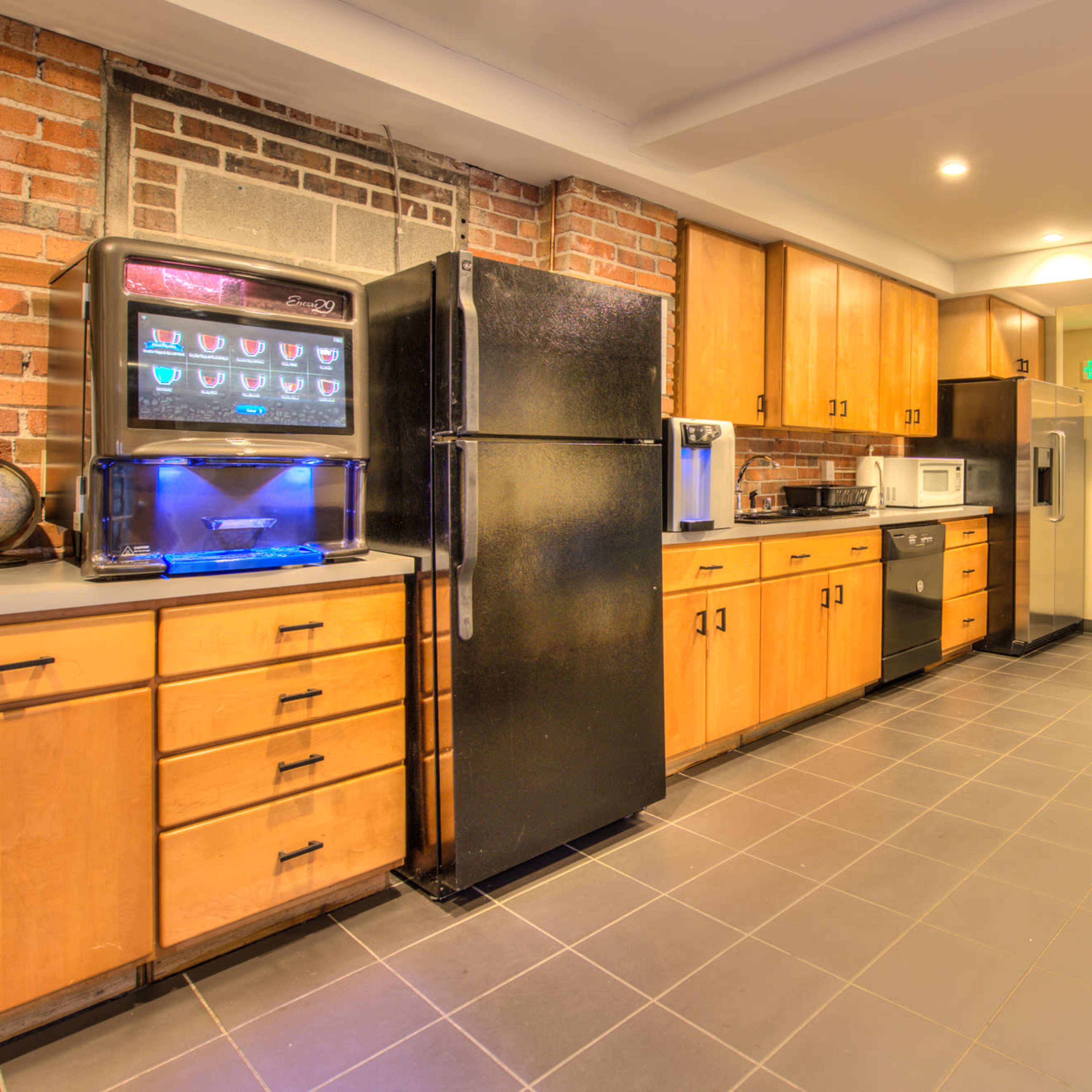 A modern kitchen with wooden cabinets, stainless steel appliances, and a bar counter with stools.