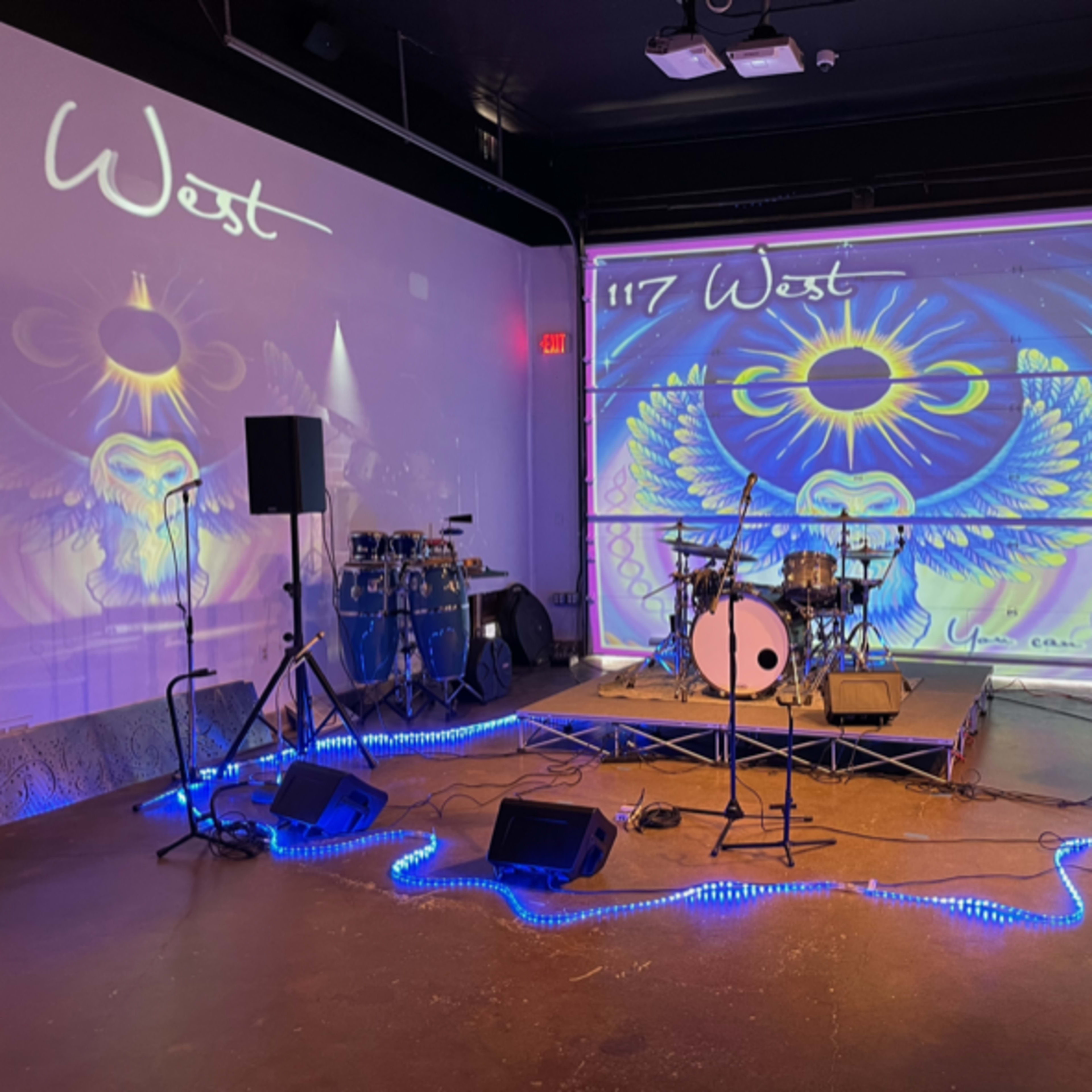 A staged performance area with a drum set, speakers, and colorful lighting, featuring a large backdrop design.