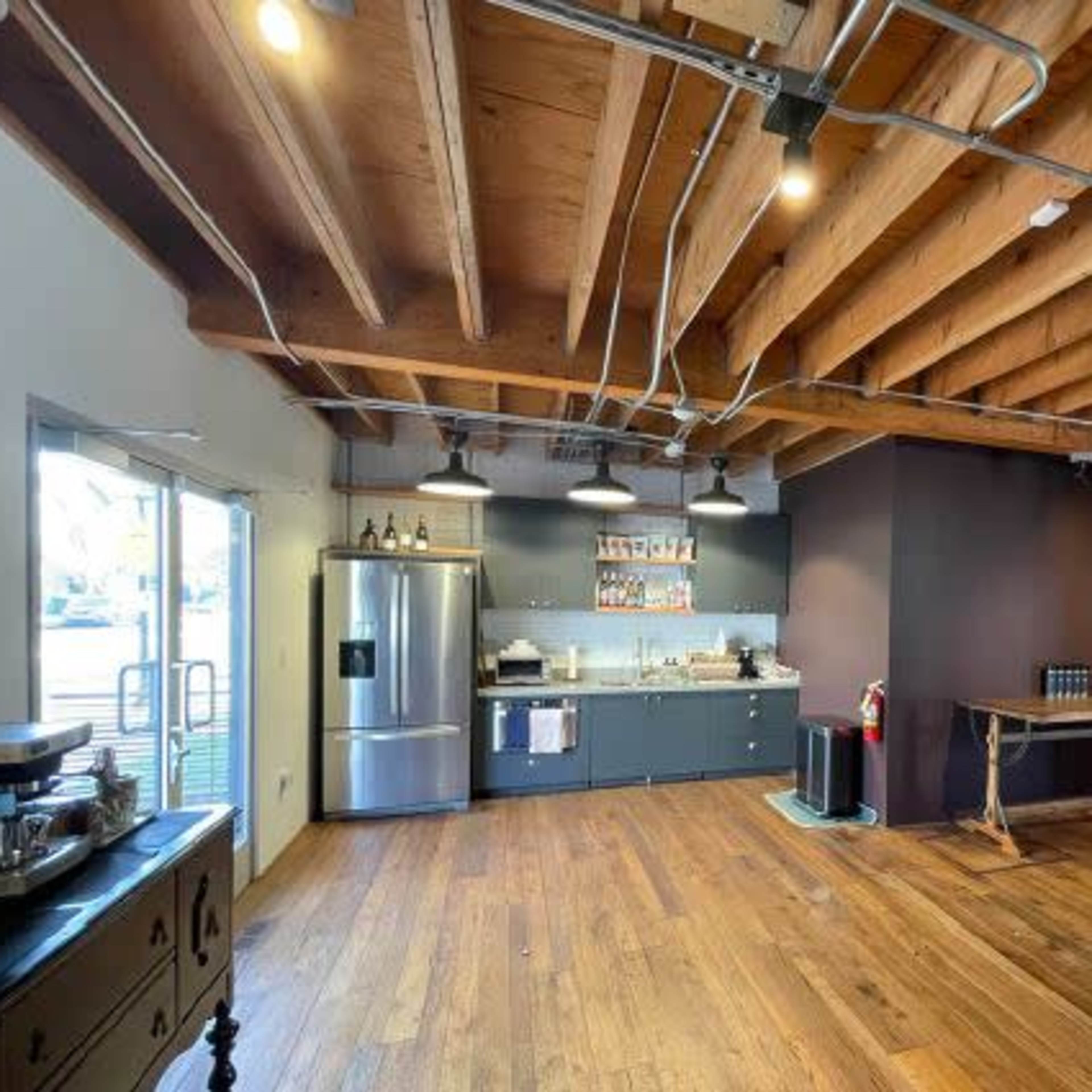 A spacious interior features wooden beams, a modern kitchen with stainless steel appliances, and hardwood flooring.