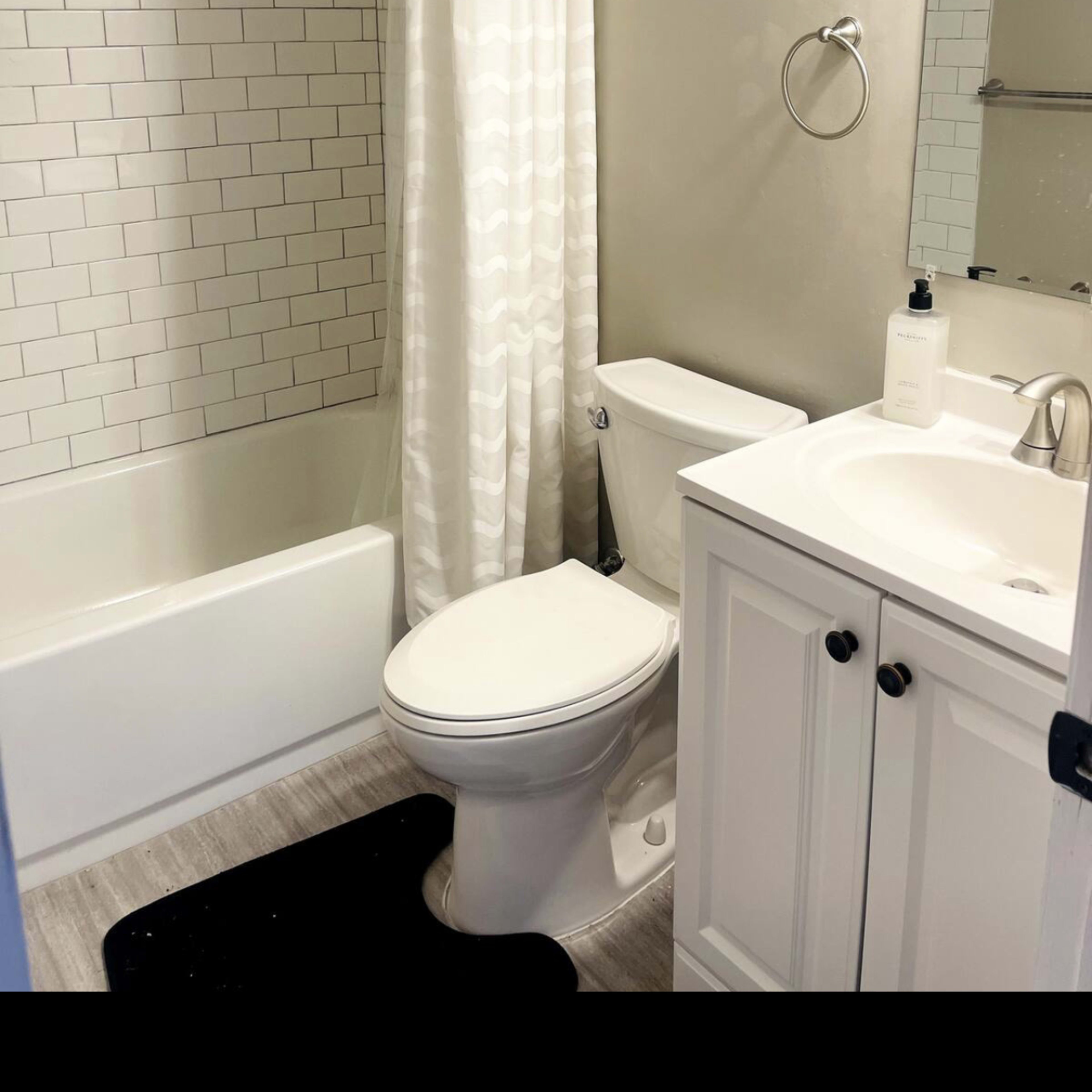 A bathroom featuring a bathtub with a shower curtain, a toilet, and a vanity with a mirror.