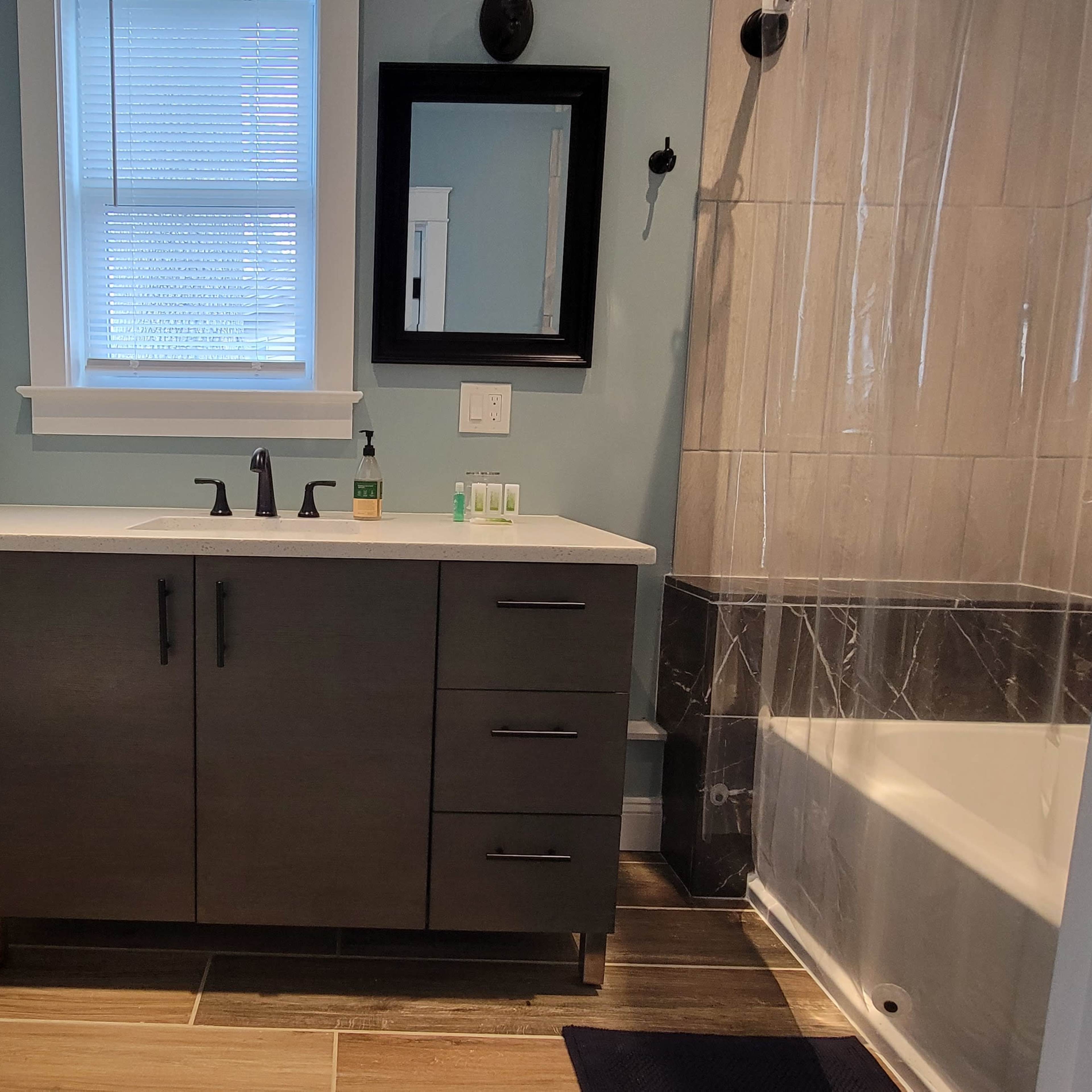 A modern bathroom featuring a toilet, a sink with a vanity, and a shower/bathtub combination with a glass curtain.