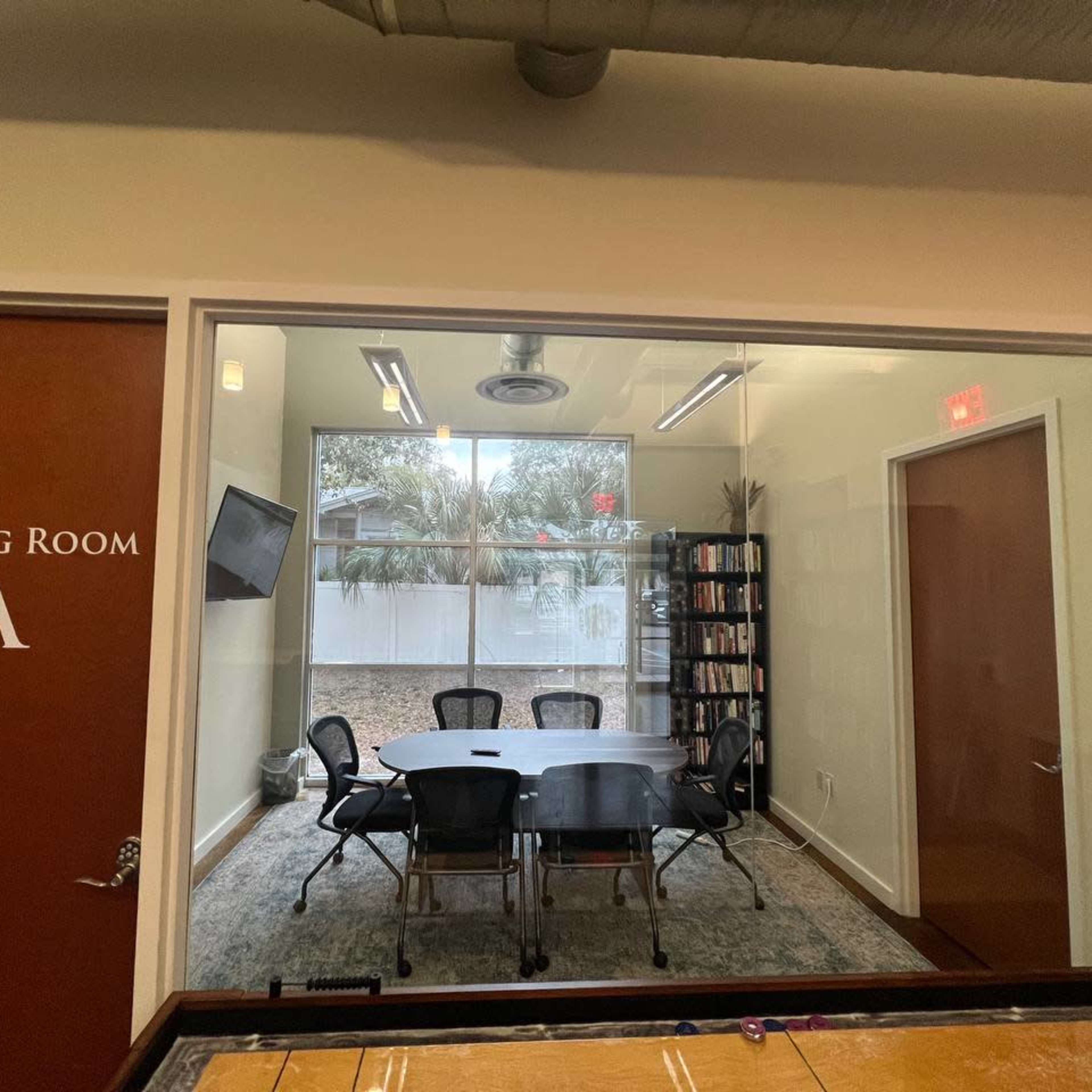 A meeting room labeled "Meeting Room A," featuring a table surrounded by chairs and a window with a view of an outdoor area.