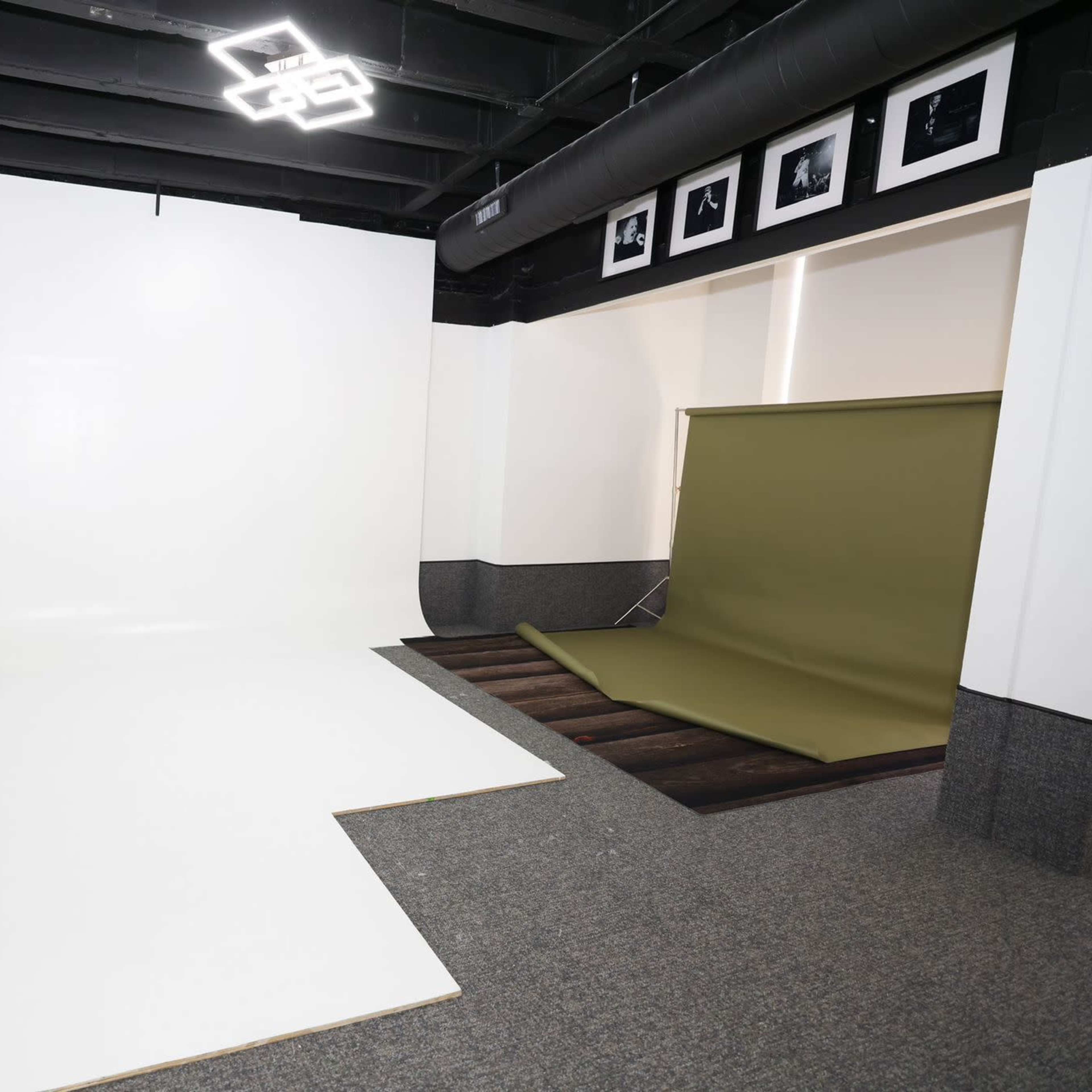 A photography studio with a white backdrop on the left and an olive green backdrop folded on the right.