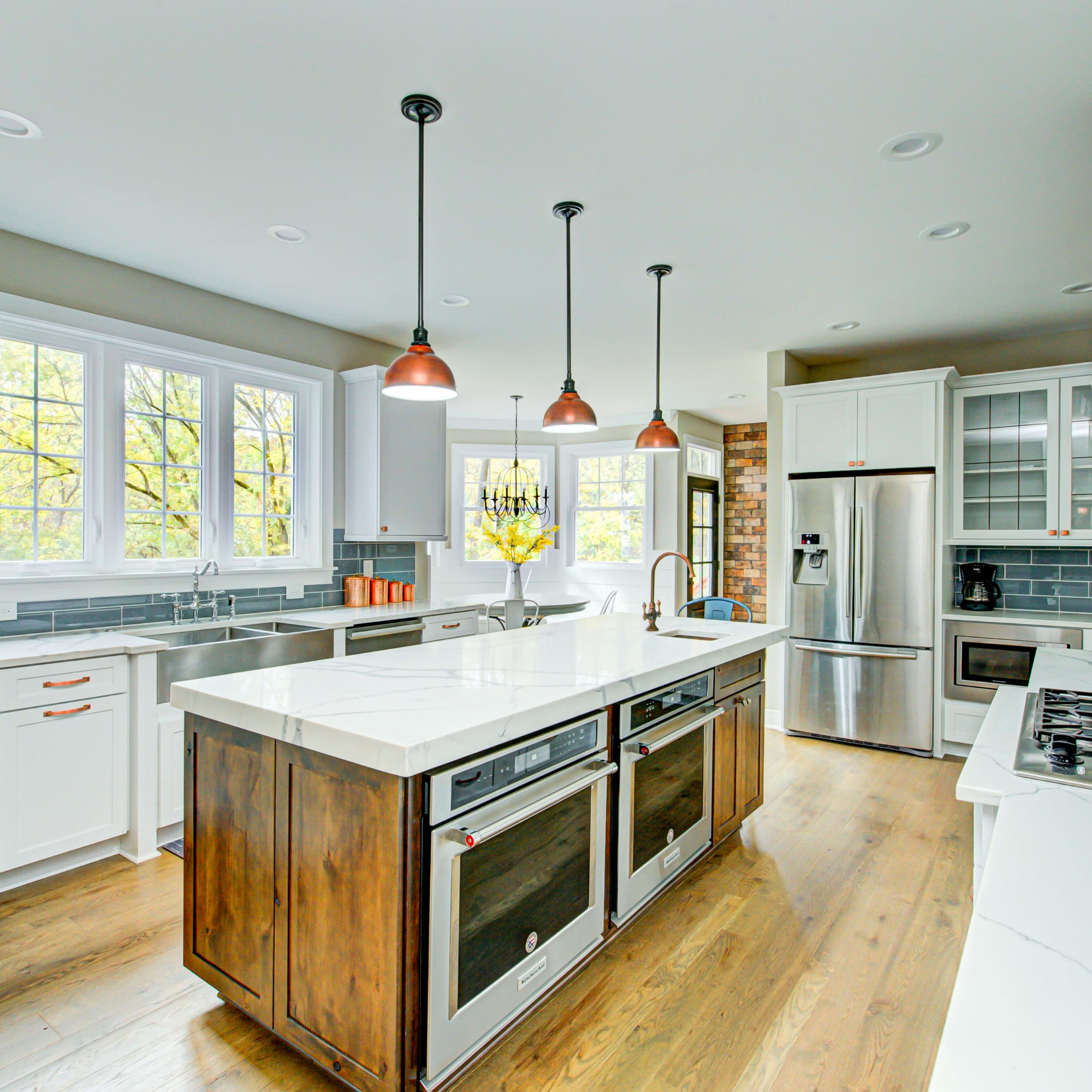 A modern kitchen features white cabinetry, stainless steel appliances, and a large island with a quartz countertop.