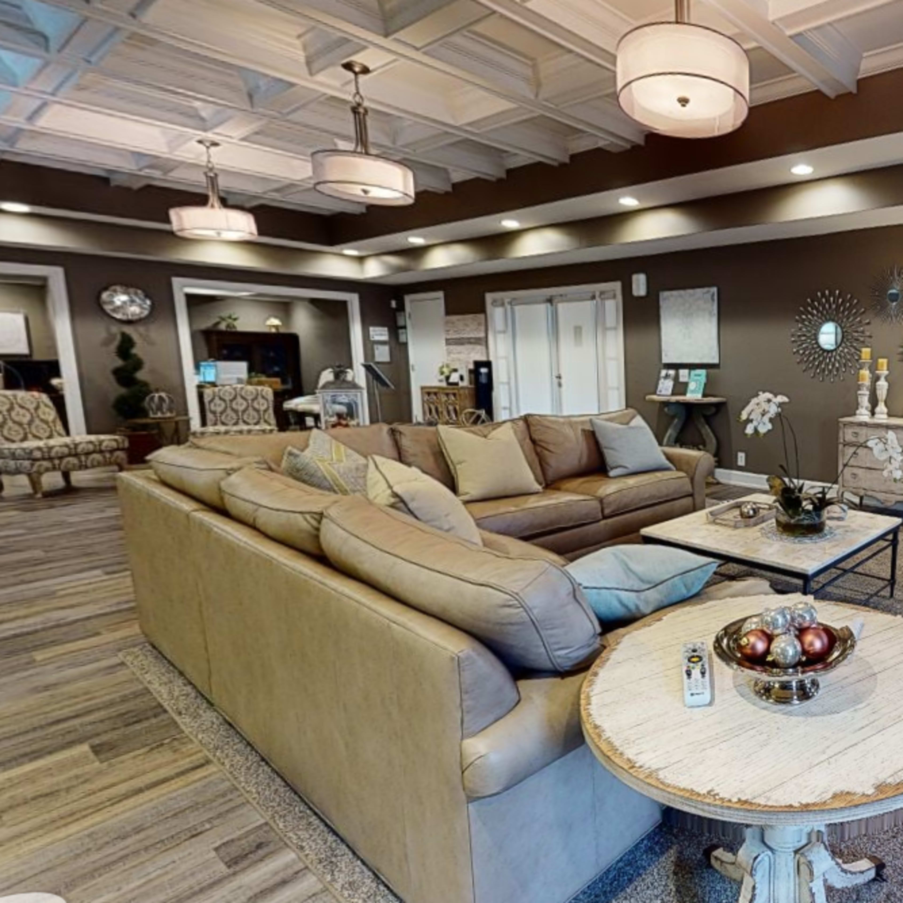 A spacious lounge area with beige sofas, a round table with decorative items, and elegant light fixtures.