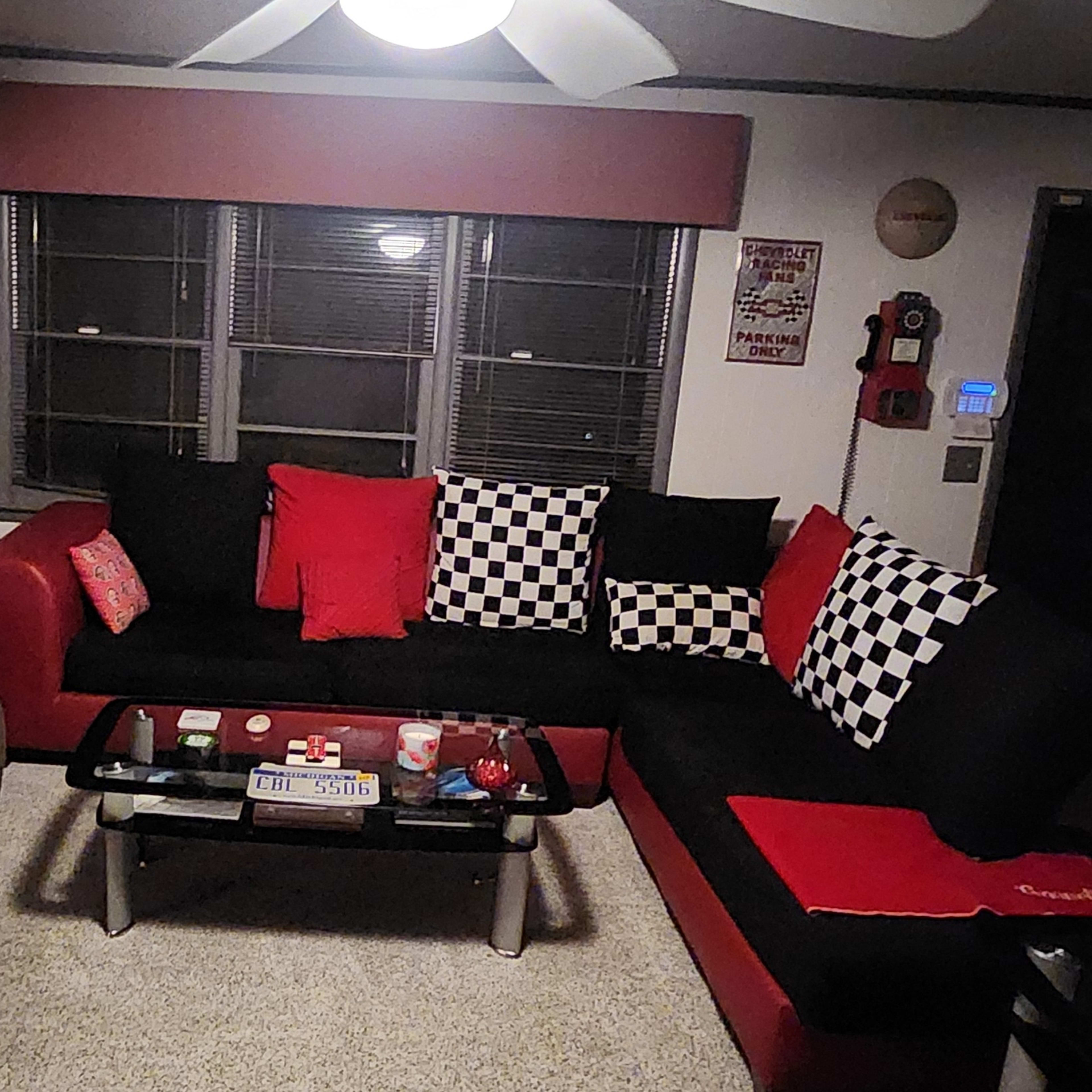 A living room with a black and red sectional sofa, a recliner, a coffee table, and a patterned black and white floor.