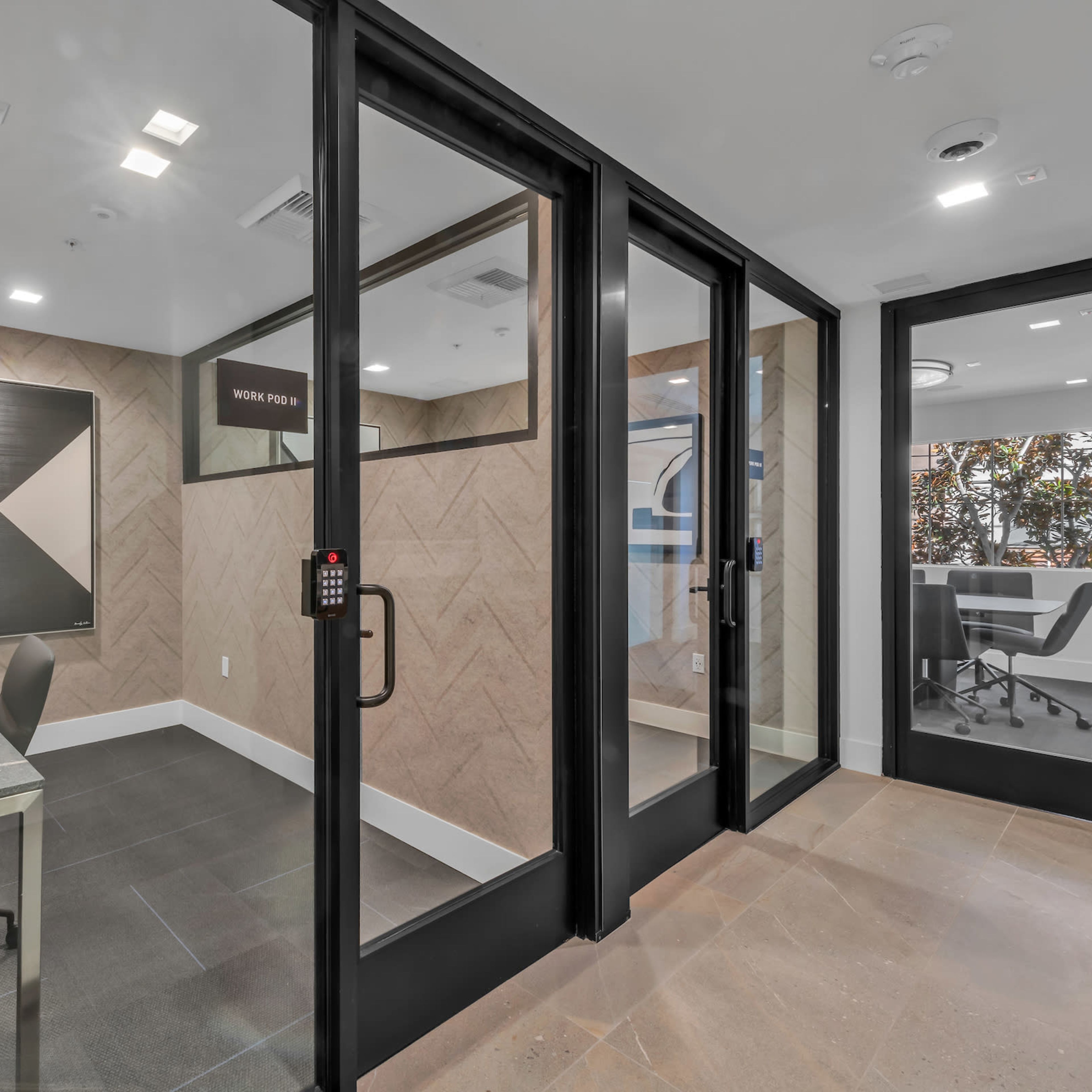 A modern office space with a glass-walled meeting room and a separate workspace featuring a table and chairs.