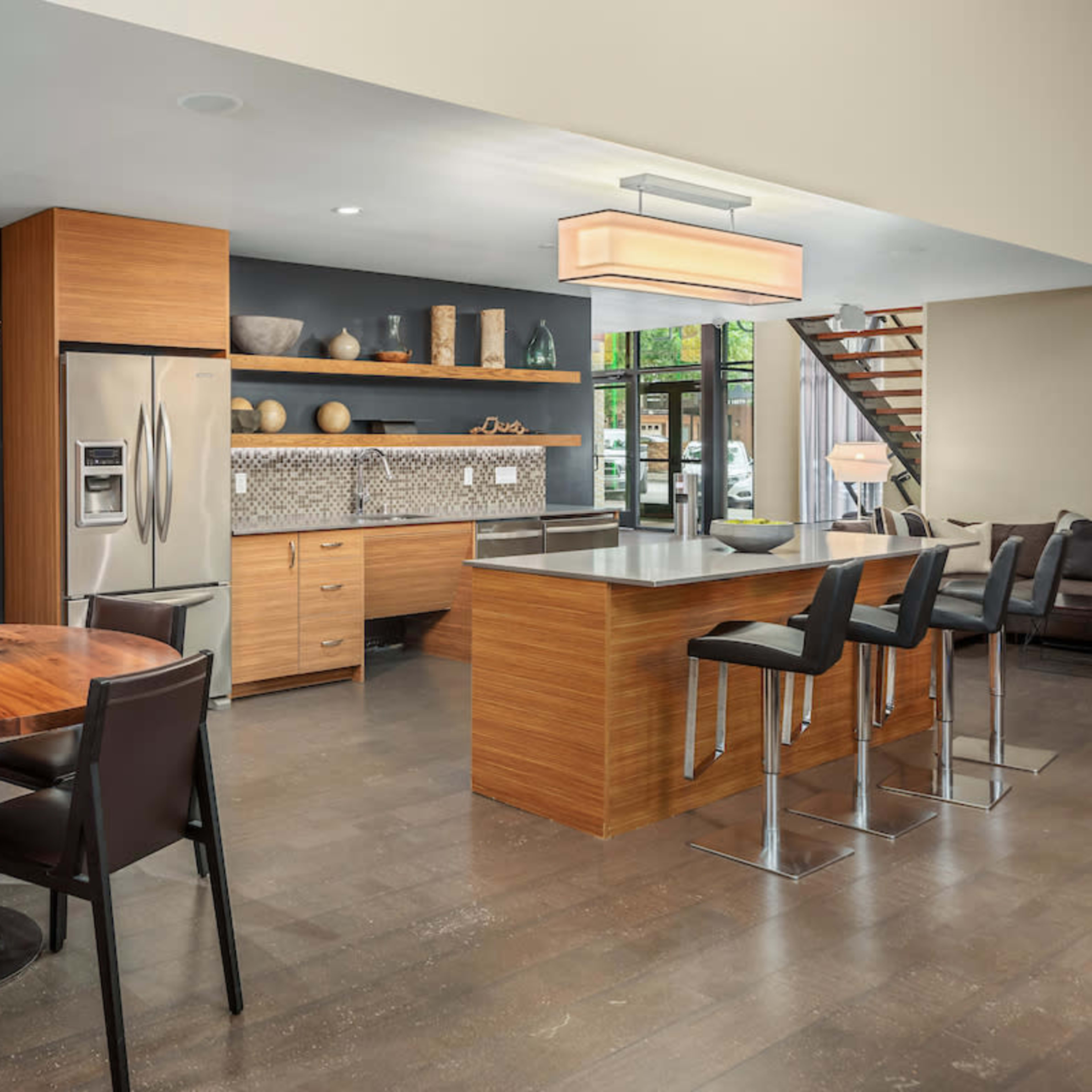 A modern kitchen and dining area featuring a round wooden table, black chairs, and sleek cabinetry with stainless steel appliances.