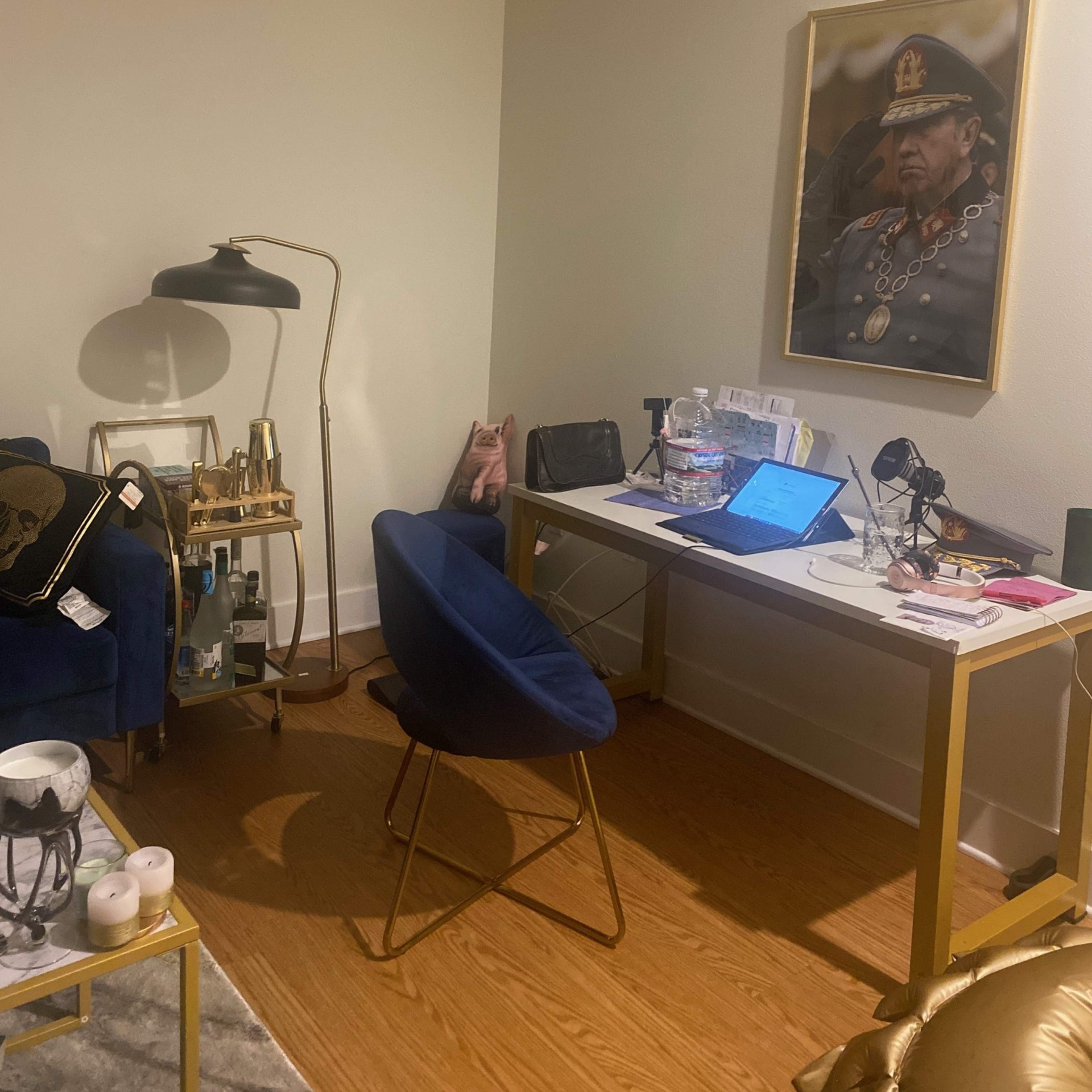 A small office space with a desk, a chair, and a portrait of a man in a military uniform on the wall.